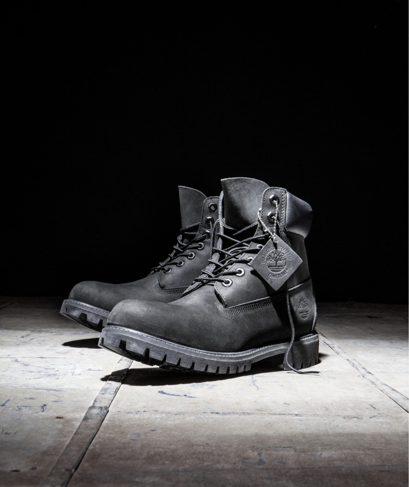 A pair of black Timberland boots on a rusty metal surface against a dark background.
