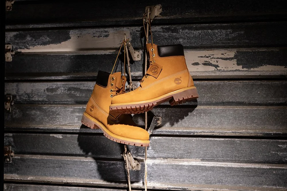 Pair of yellow Timberland boots hanging on a rustic wall.