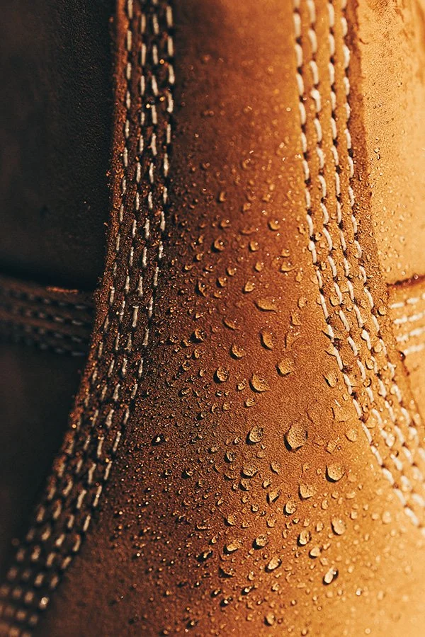 Close-up of the back of a Timberland yellow boot with water droplets on it, showcasing the waterproof nubuck material.
