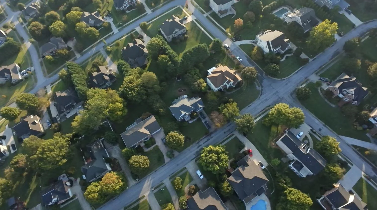 An aerial view of a suburban neighborhood with houses, trees, and streets.