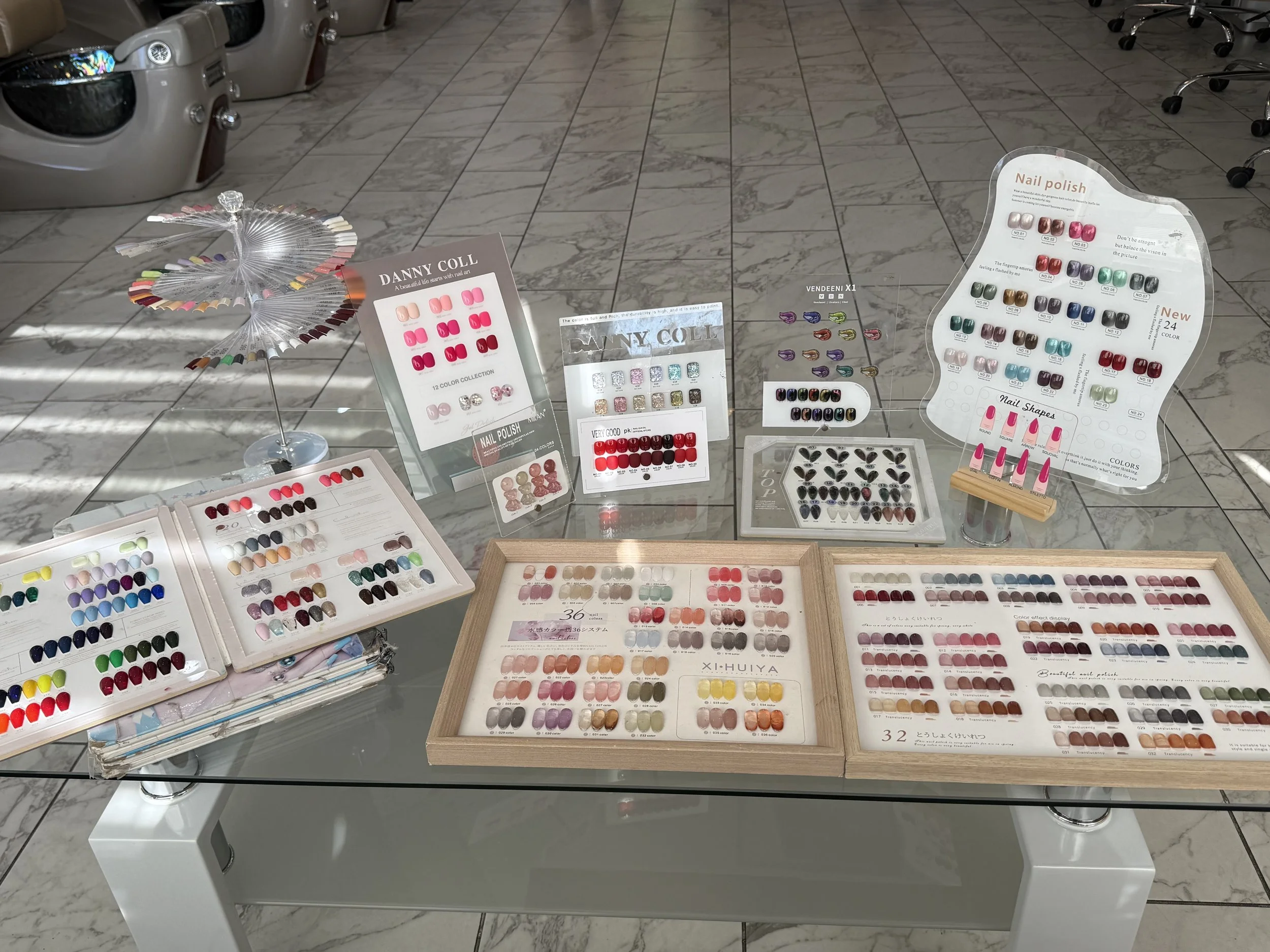 Display of various nail polish color samples on a glass table at a salon or showroom.