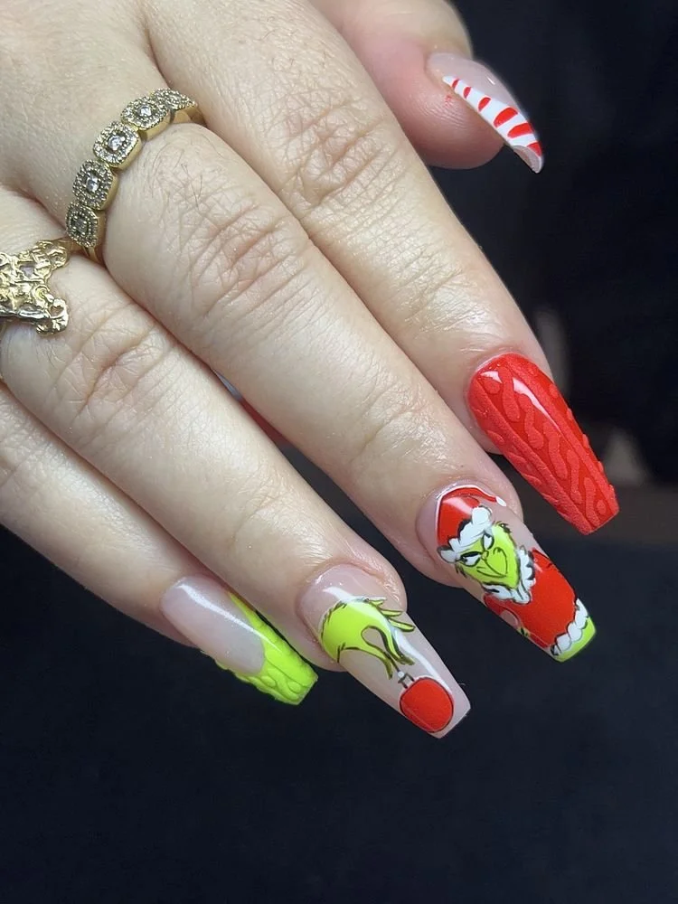 Christmas-themed manicured nails with red, green, and white nail art, featuring a grinch, Santa hat, and candy cane designs.