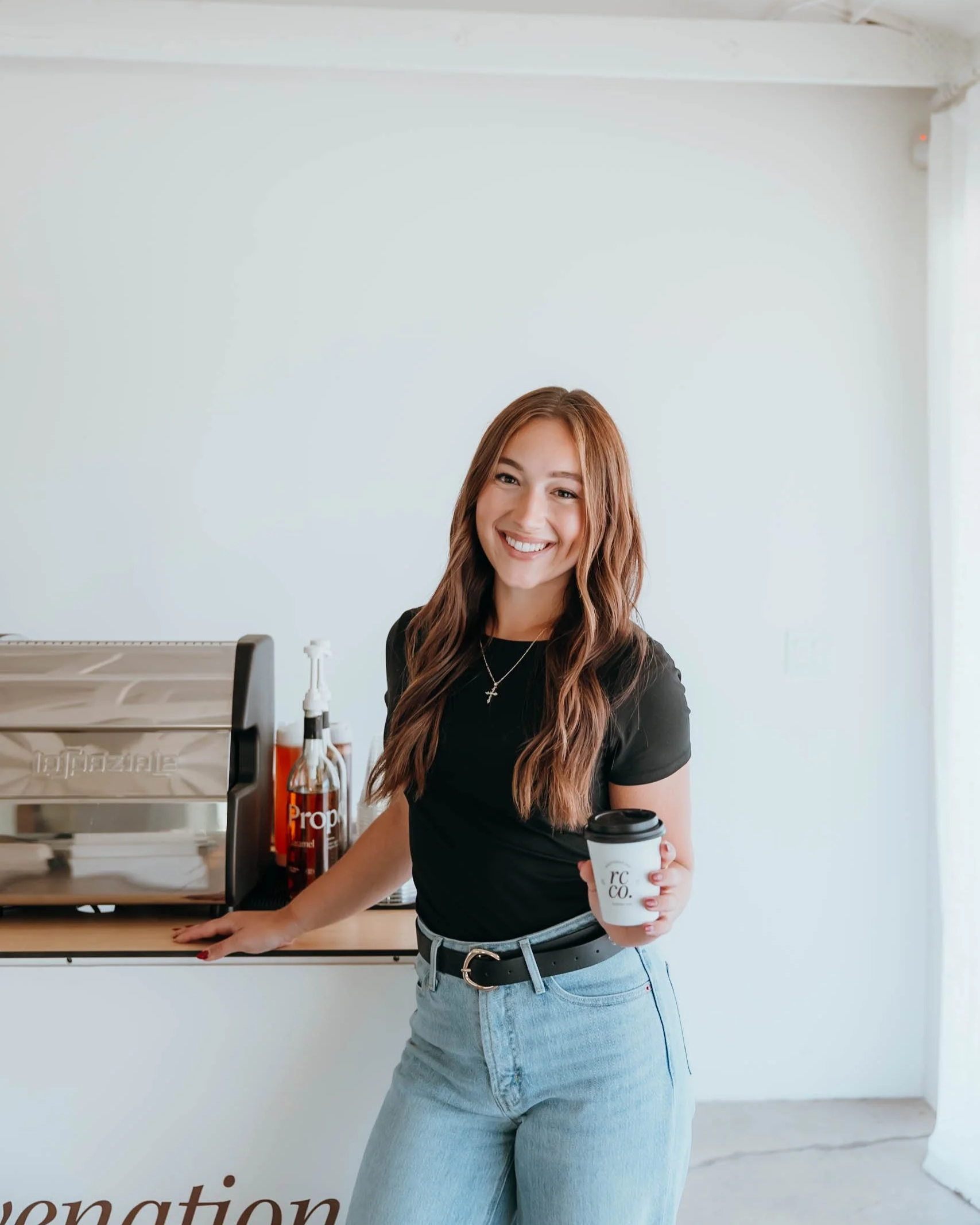 A young woman with showing a coffee that was created by Rejuvenation Coffee Co in Phoenix Arizona.