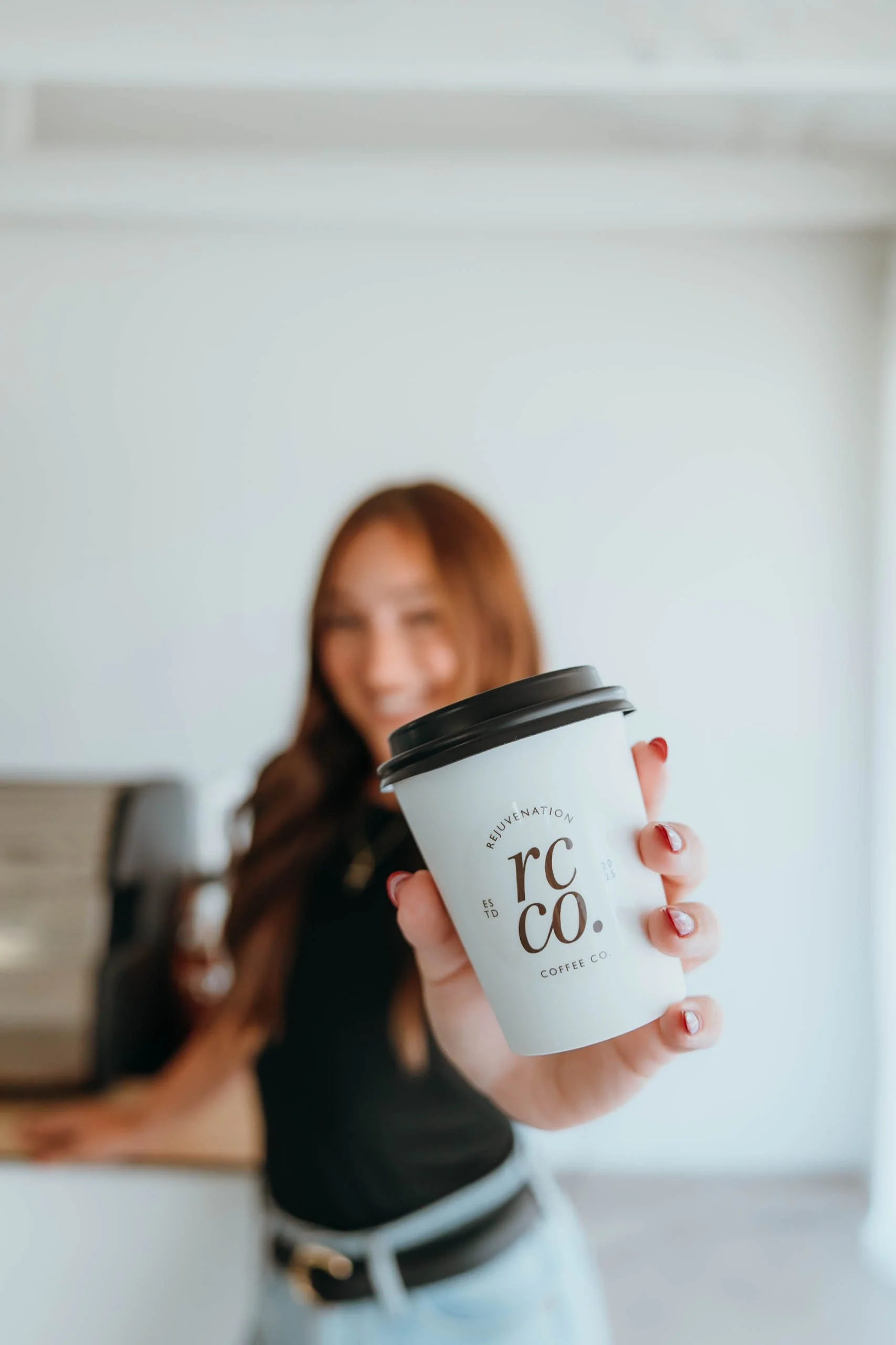 Professional barista holding a hot Rejuvenation Coffee Co. cup, showcasing the mobile coffee brand and its specialty coffee experience.