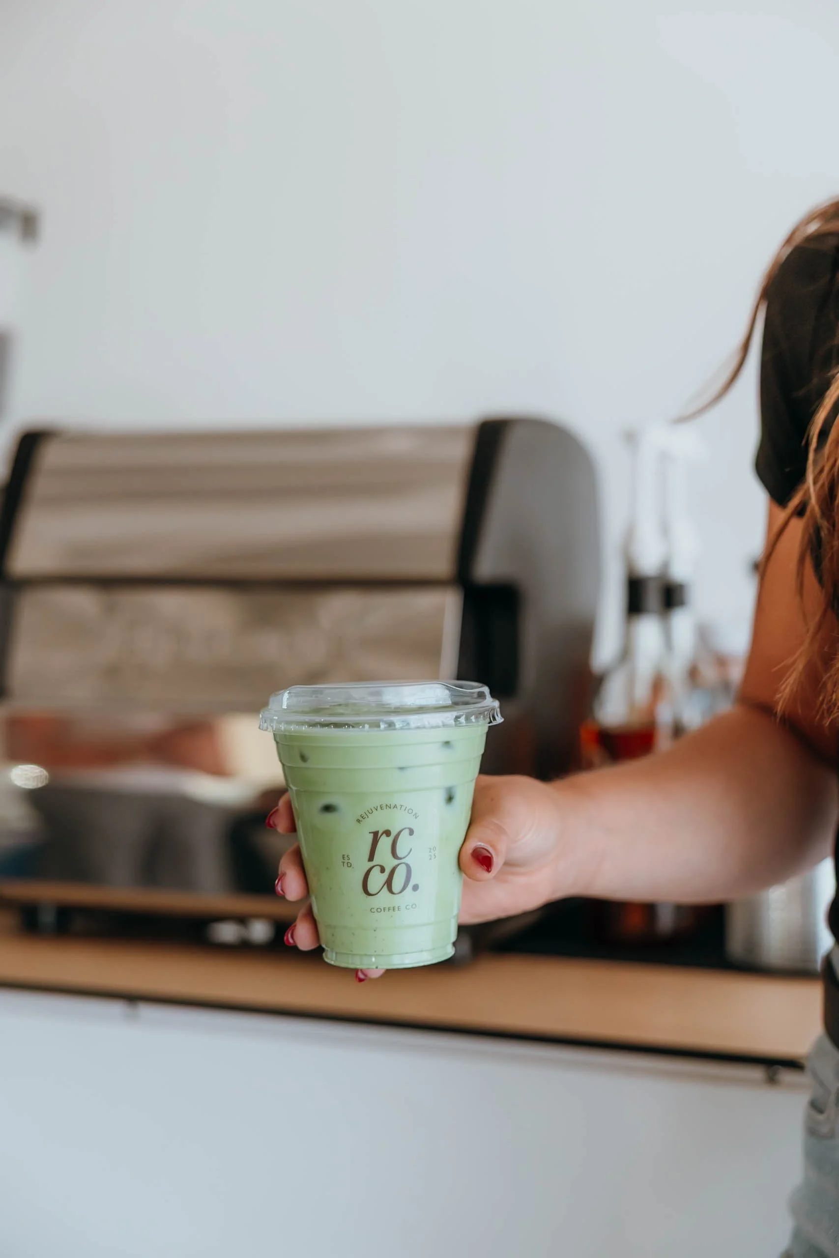 Rejuvenation Coffee Cart Owner holding a matcha before giving it to a client at an event.