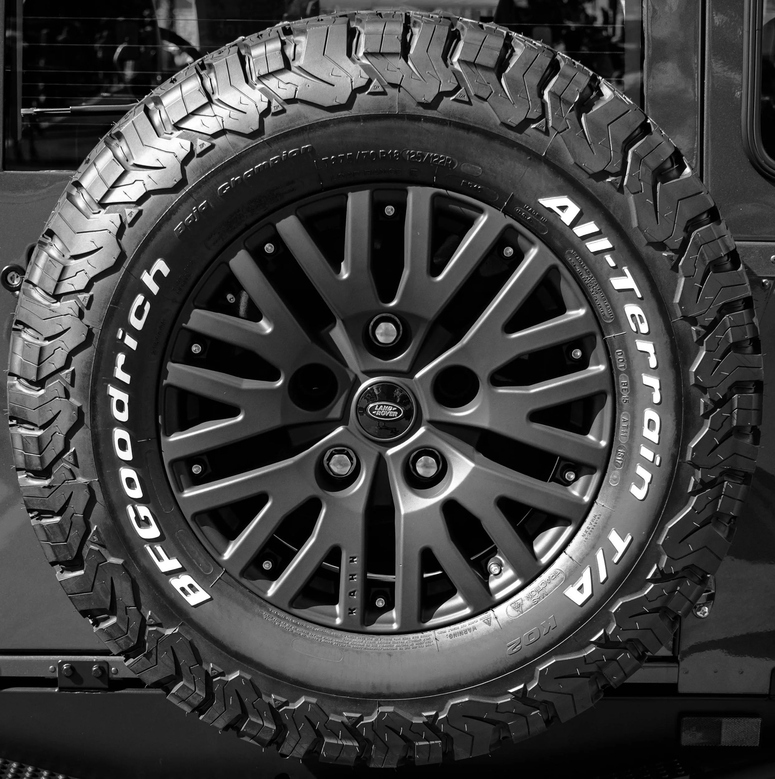 Close-up of a vehicle's wheel with a Land Rover logo, black alloy rim, and Goodyear Tire All-Terrain tire.