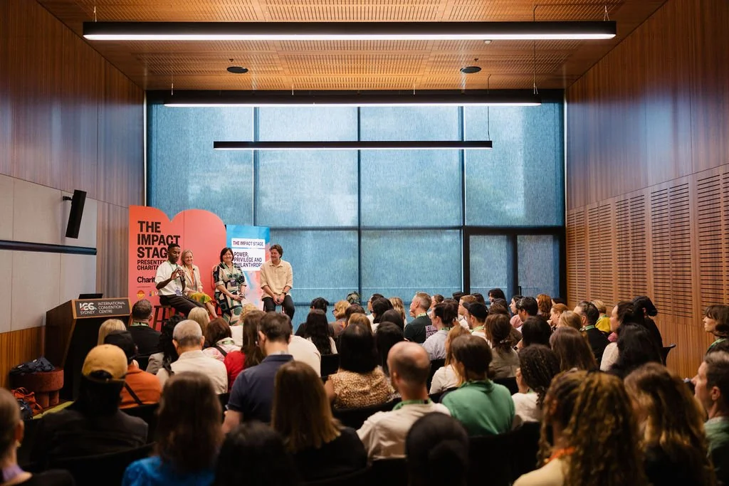 A panel discussion at a conference with four speakers on stage, at the 2025 Impact Stage.