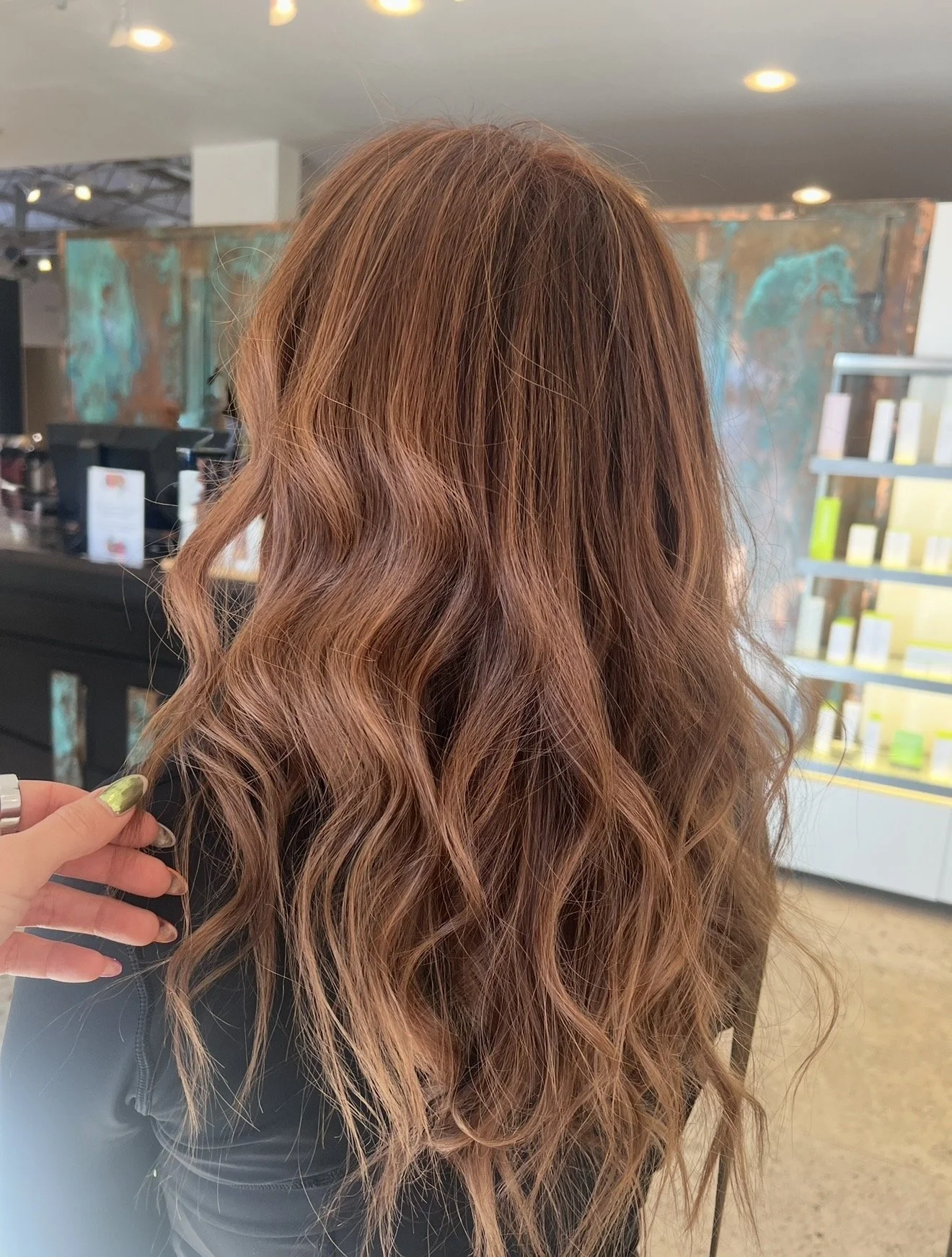 A woman with long, wavy, reddish-brown hair in a salon.