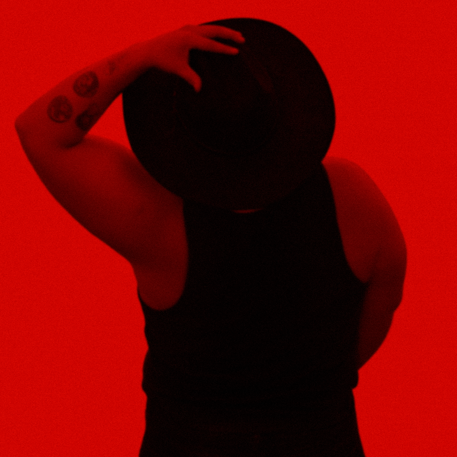 Persona con carrito de golf en un ambiente con iluminación roja, usando ropa negra y mostrando tatuajes en el brazo.