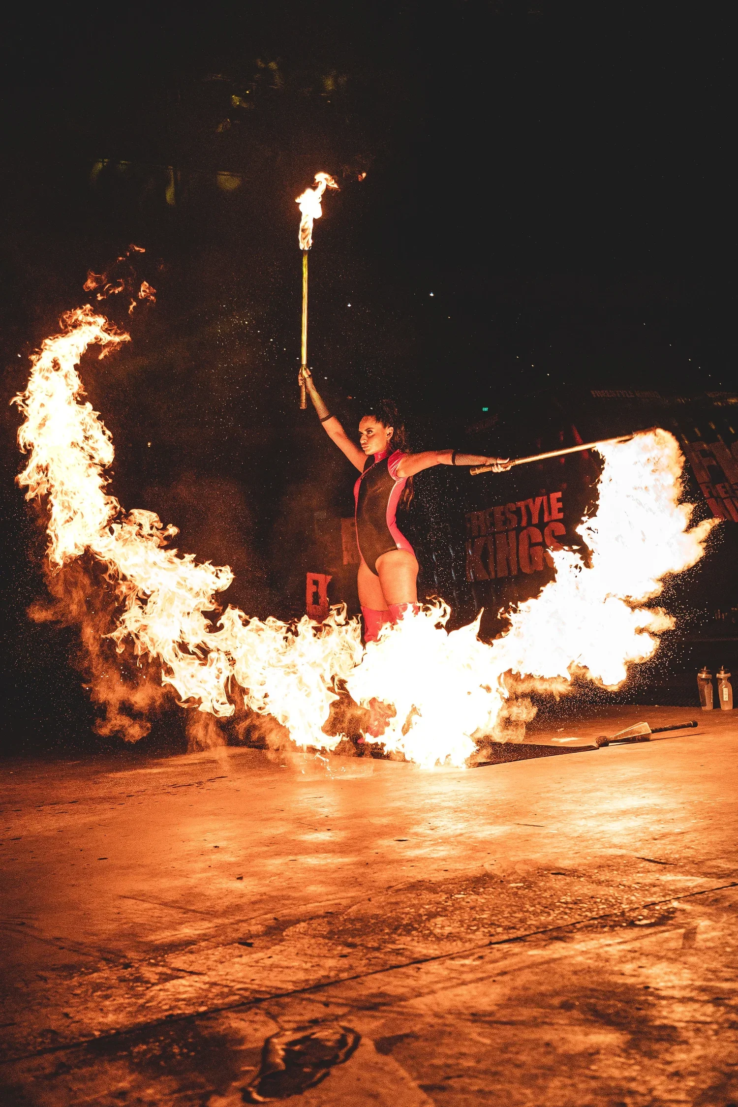 A fire breathing performer with flames around her at a Freestyle Kings event.