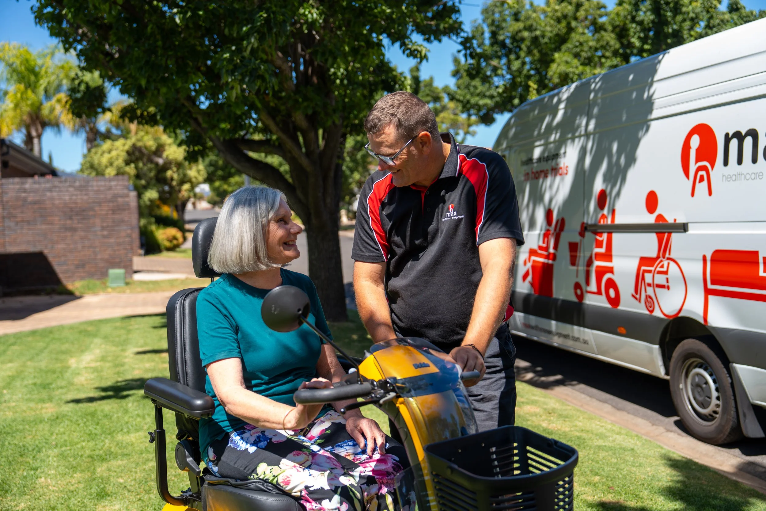 a male healthcare equipment worker showing an elderly woman an electric scooter