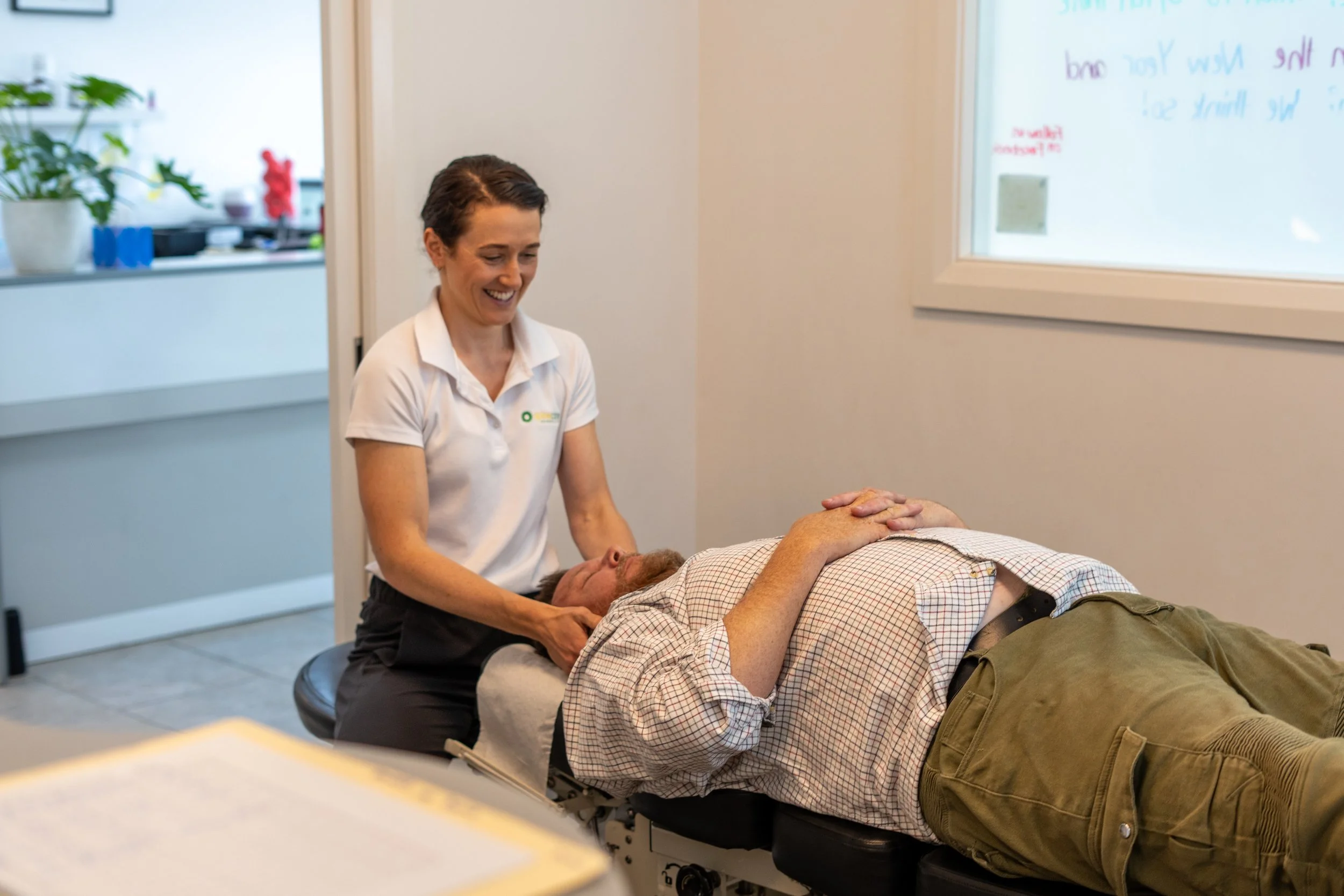 a female chiropractor smiling as she treats a male client