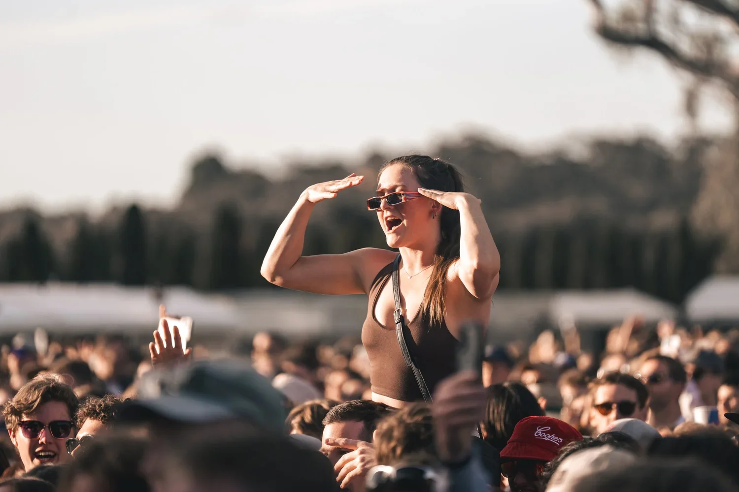 women sitting on shoulders in a crowd who are signing, smiling and dancing at a music festival in McLaren Vale, South Australia