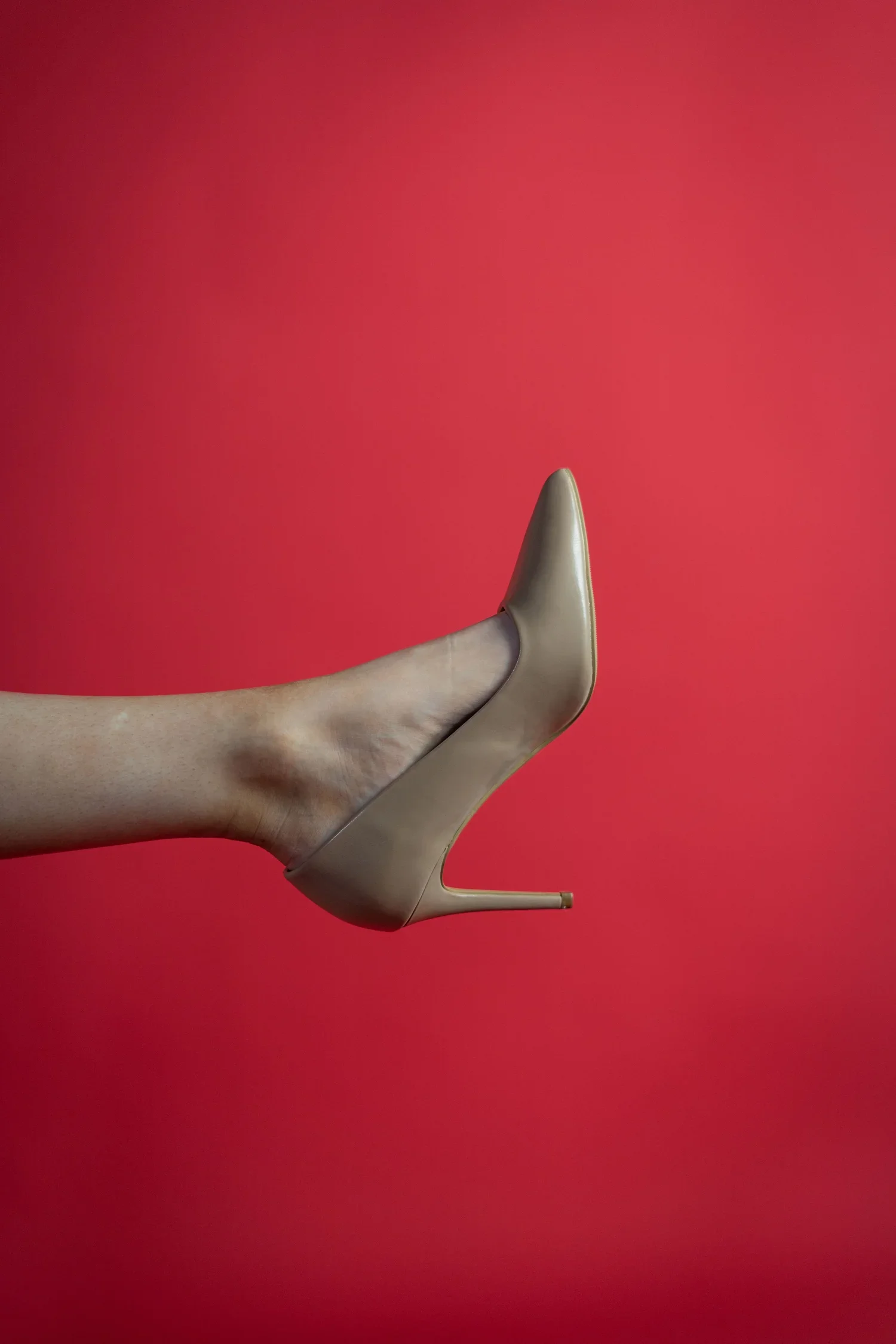 woman wearing a high heel in front of a red background