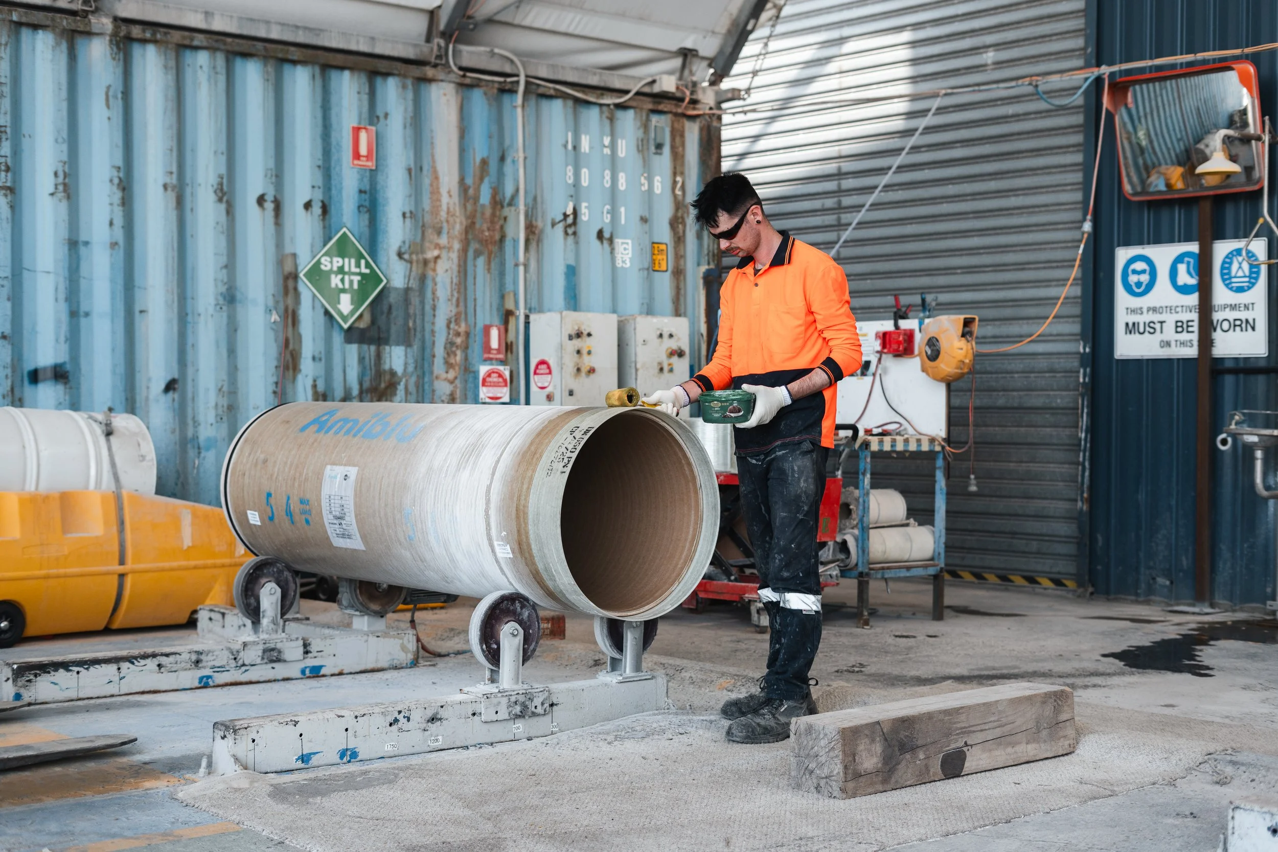 A worker coating an industrial size pipe