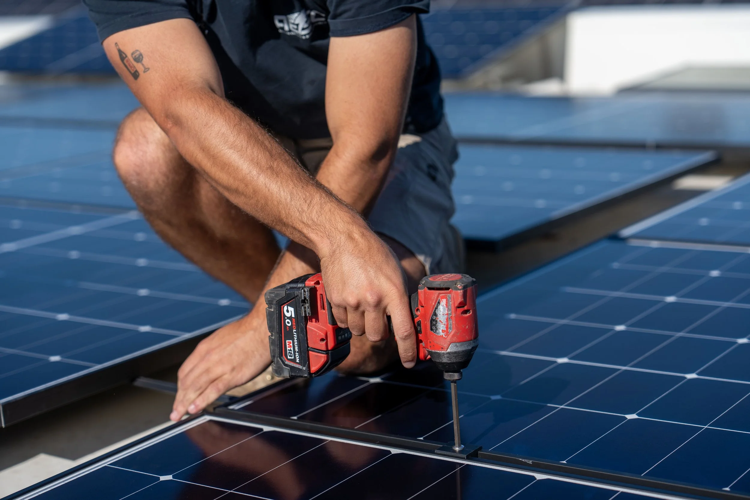 worker using drill to install solar panels