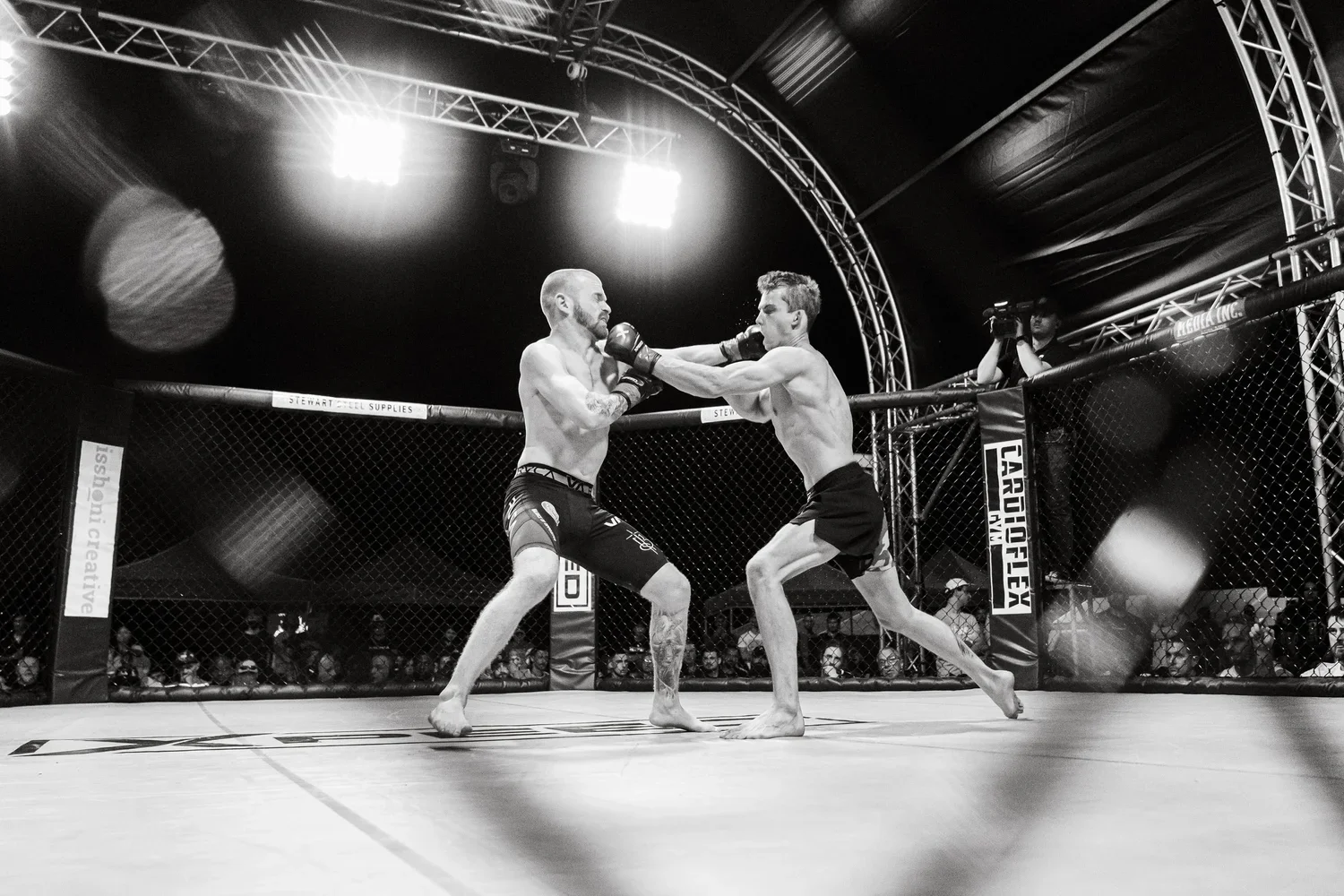 Two MMA fighters punching each other in the face at an MMA event