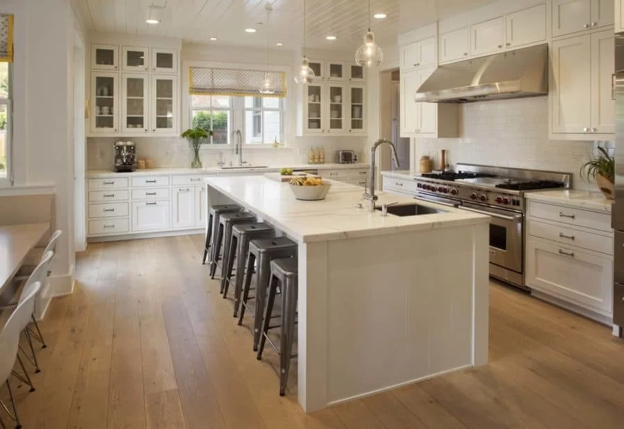 Bright, modern white kitchen with an island, stainless steel appliances, and natural light.