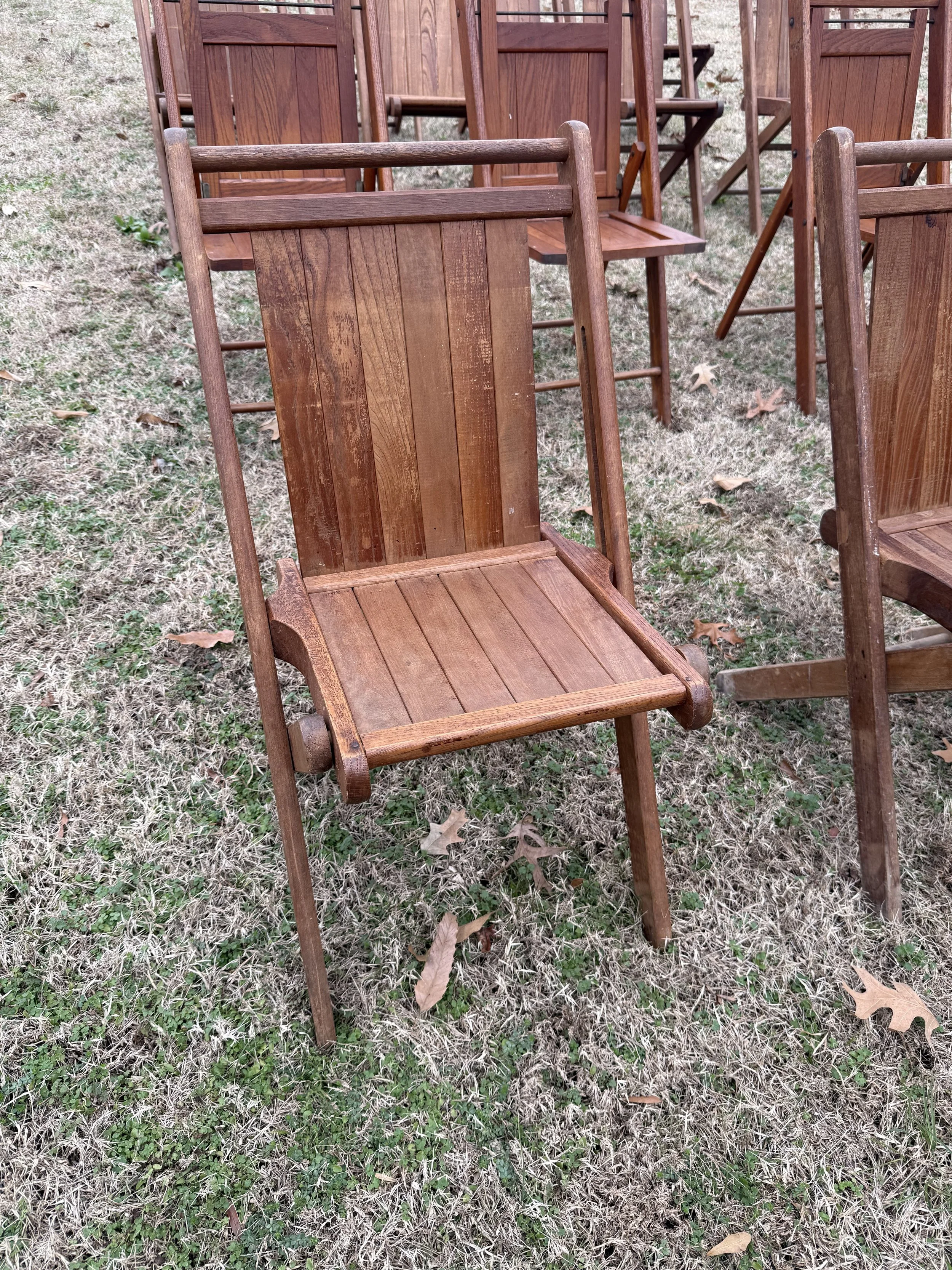 Row of wooden chairs outdoors on grass.