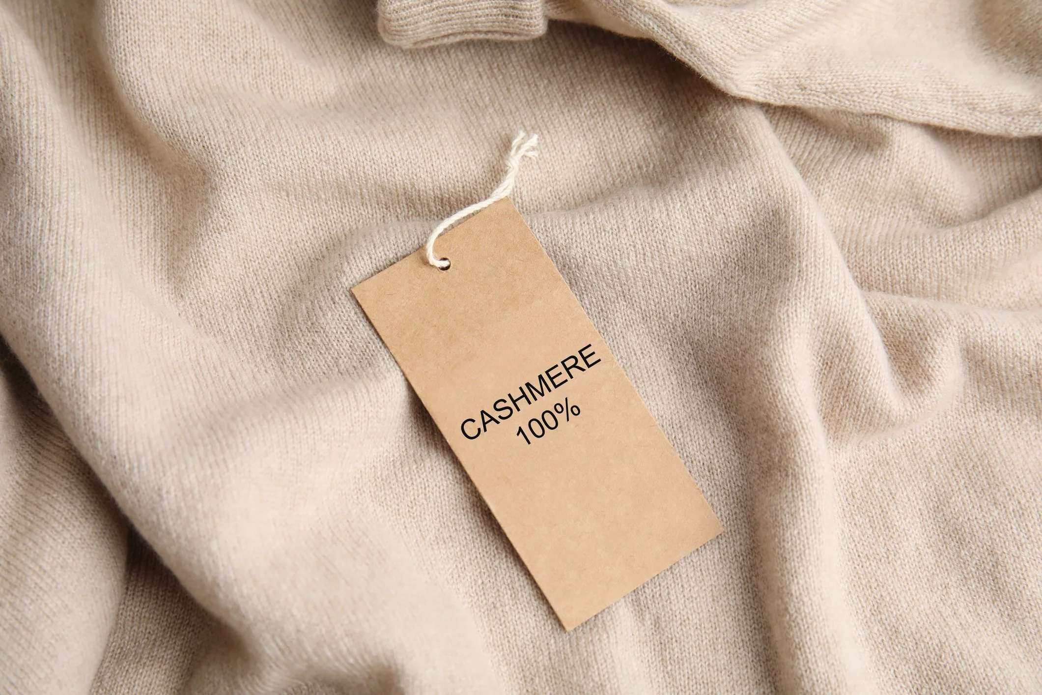 Cream-colored cashmere fabric with a brown tag that reads 'CASHMERE 100%'.