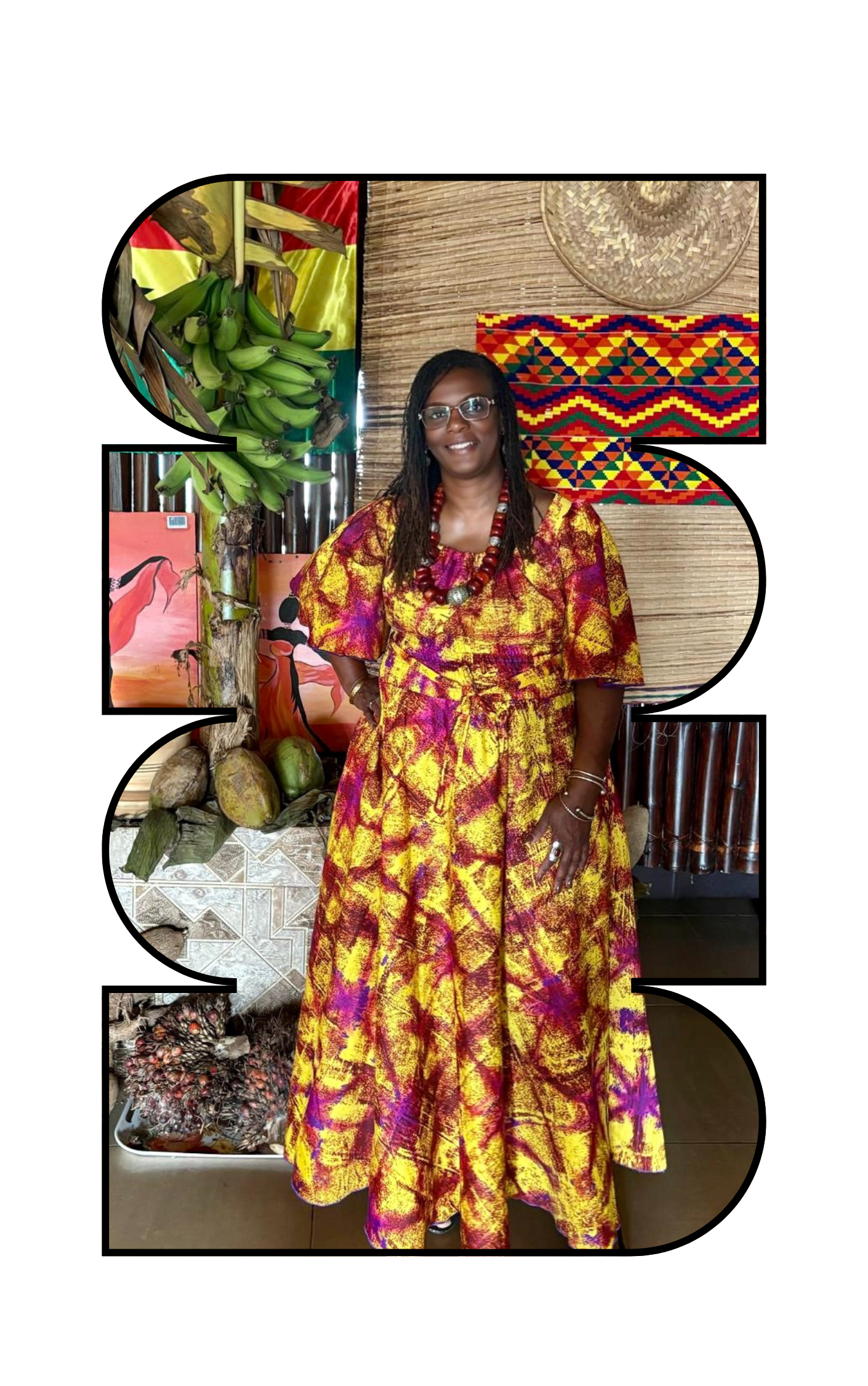 A woman wearing a colorful yellow and purple dress standing in front of a decorated backdrop with African art, painted coconuts, and banana plants.