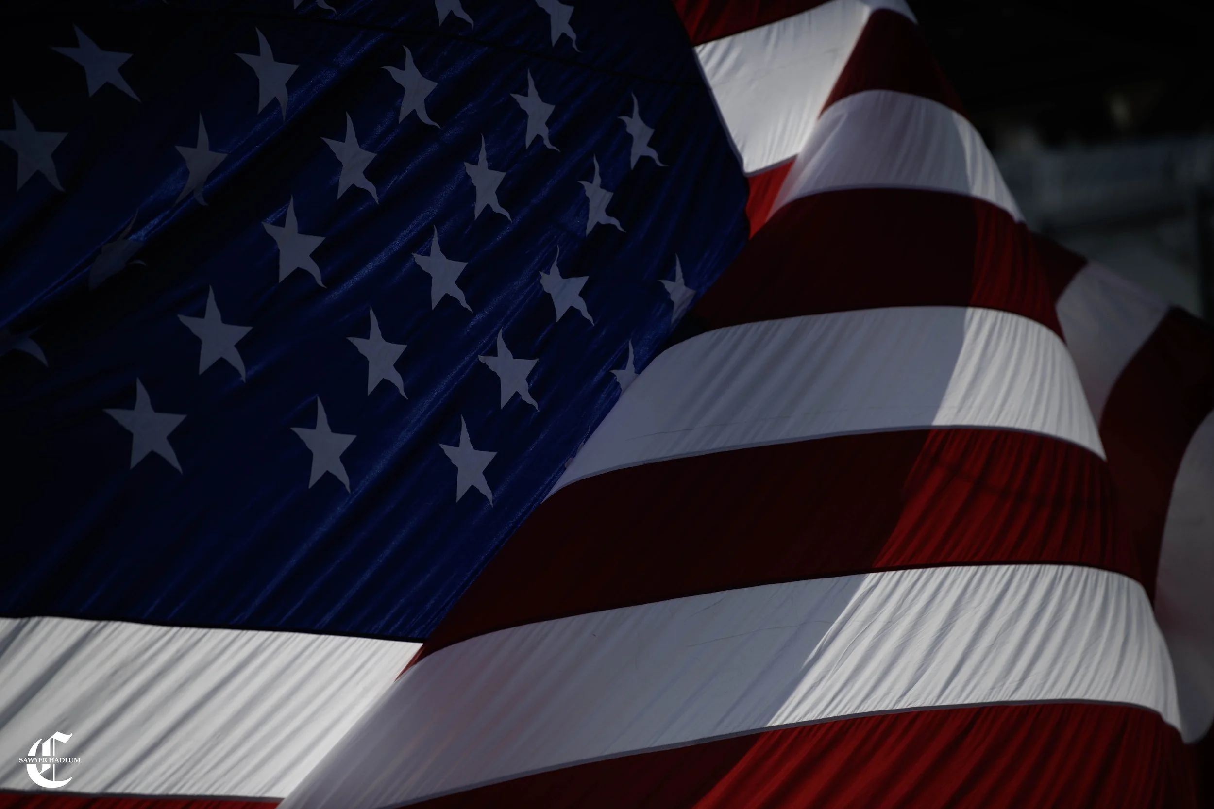 Close-up of a hanging U.S. flag with red and white stripes and white stars on a blue background.