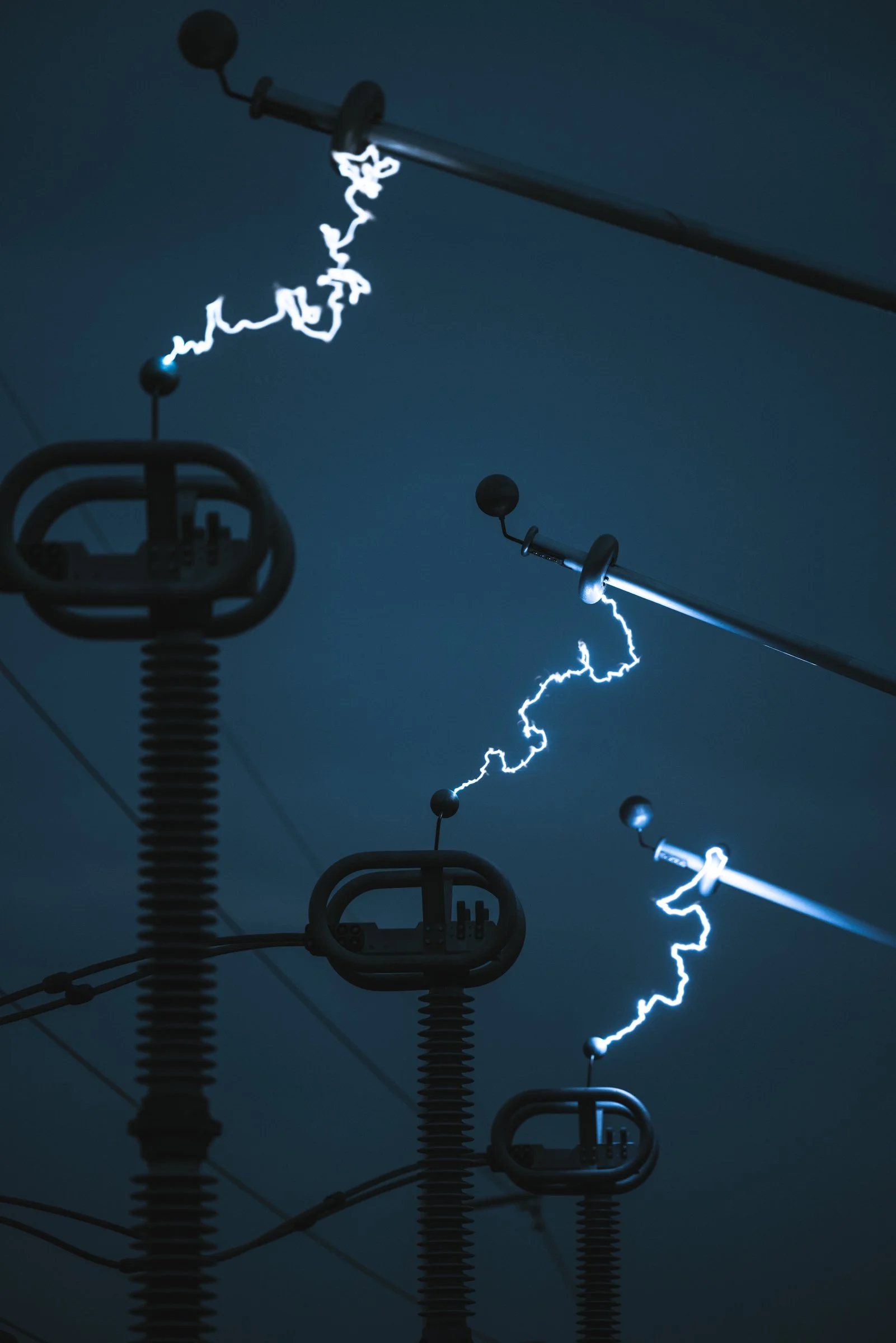 Power lines with visible lightning discharge striking the cables in the dark night sky.