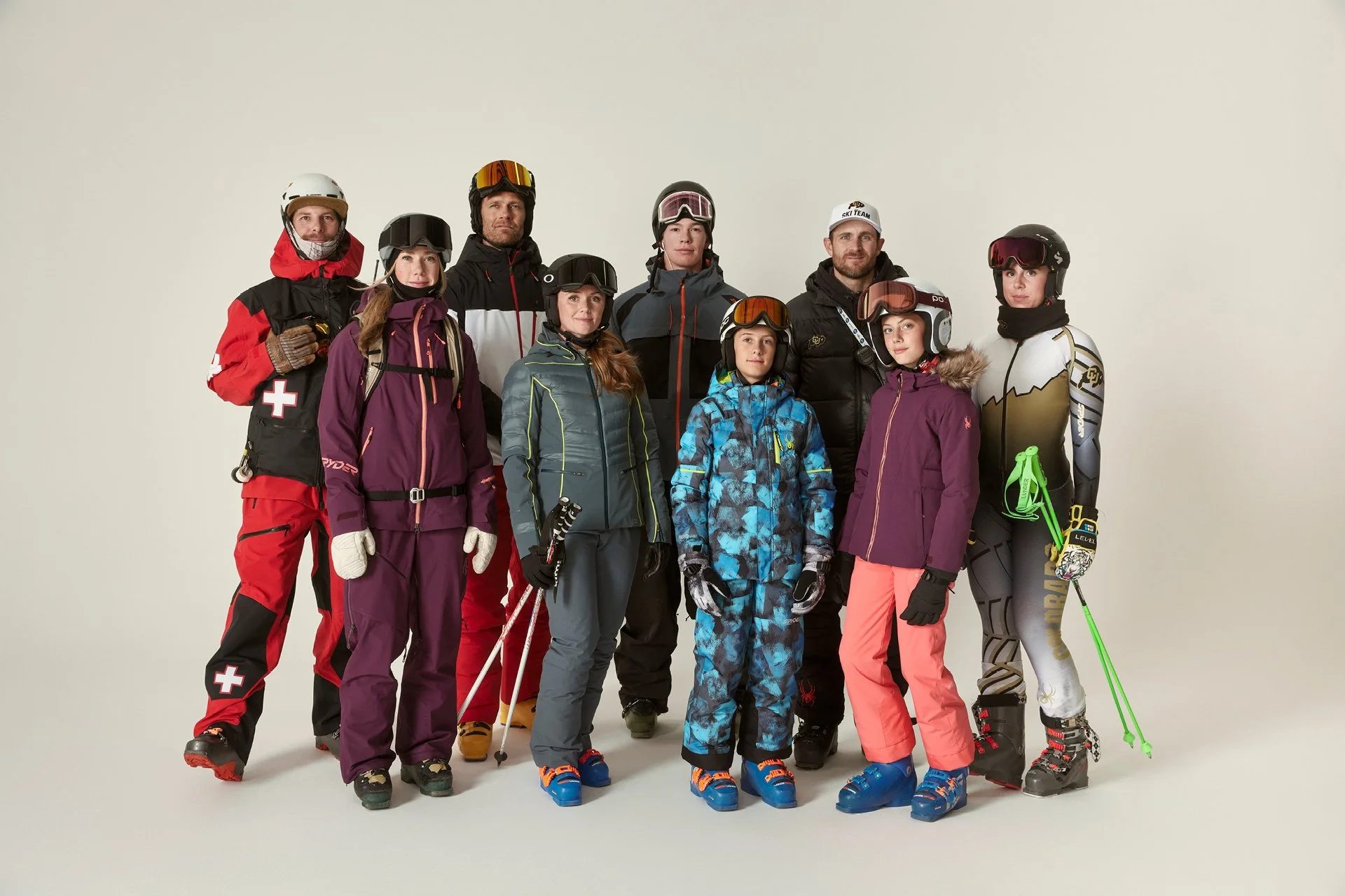 Group of people in ski gear standing against a plain white background.