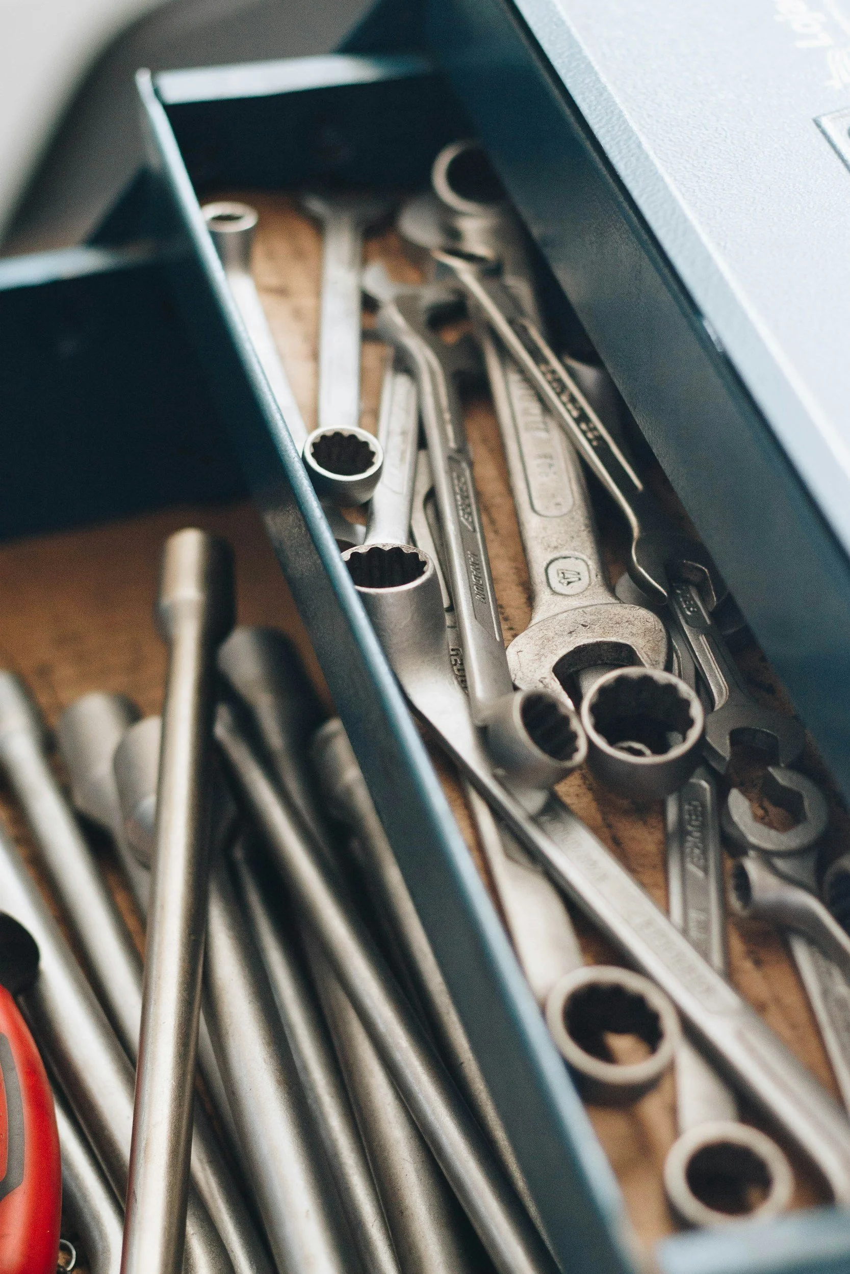 A toolbox with various metal wrenches and tools inside, scattered on a wooden surface.