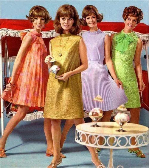 Four women in colorful 1960s dresses standing in a room with a table of ice cream sundaes.