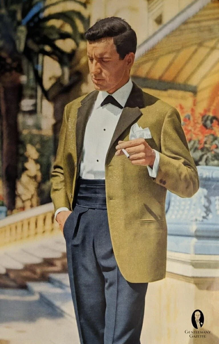 Man in a tuxedo with a gold blazer, holding a cigarette, standing in a vintage setting.