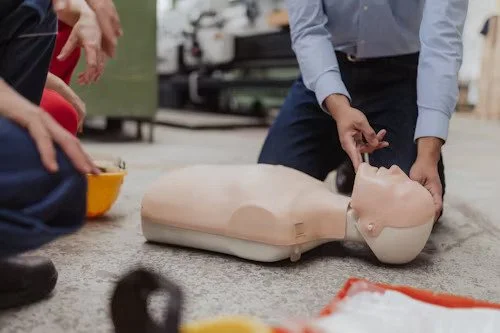 Person practicing CPR on a training manikin on the floor