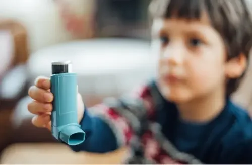 Child holding a blue inhaler.