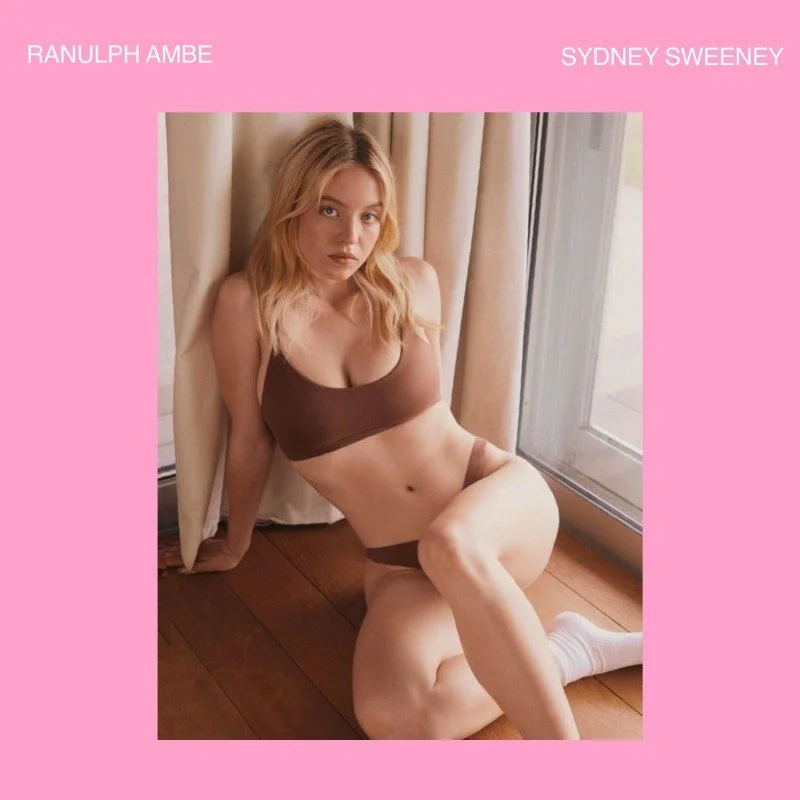 A woman with blonde hair sitting on the wooden floor next to a window, wearing brown underwear, with beige curtains and a pink background with white text.