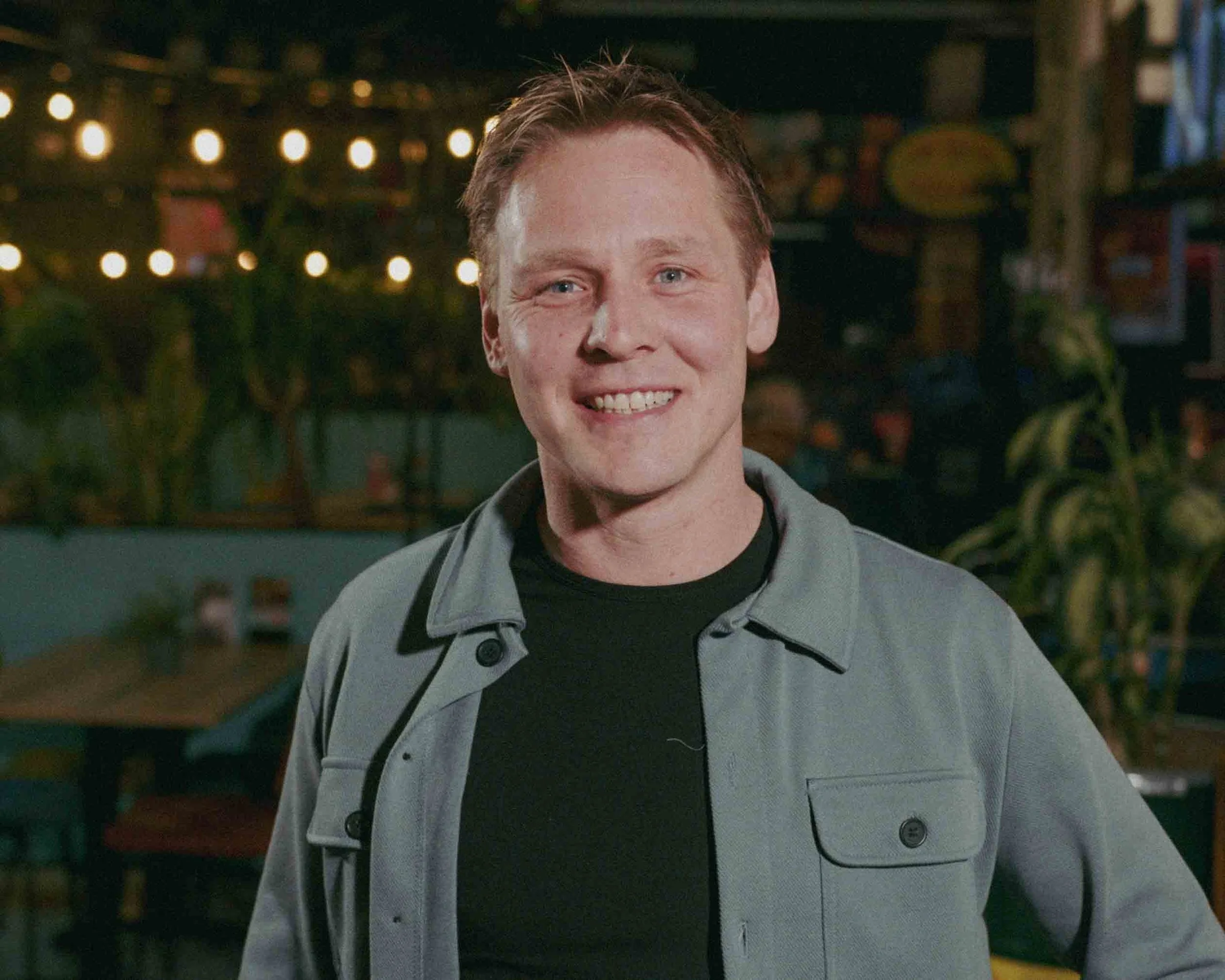 Two men are kneeling on grass in an emotional moment, with one covering his face and the other comforting him.