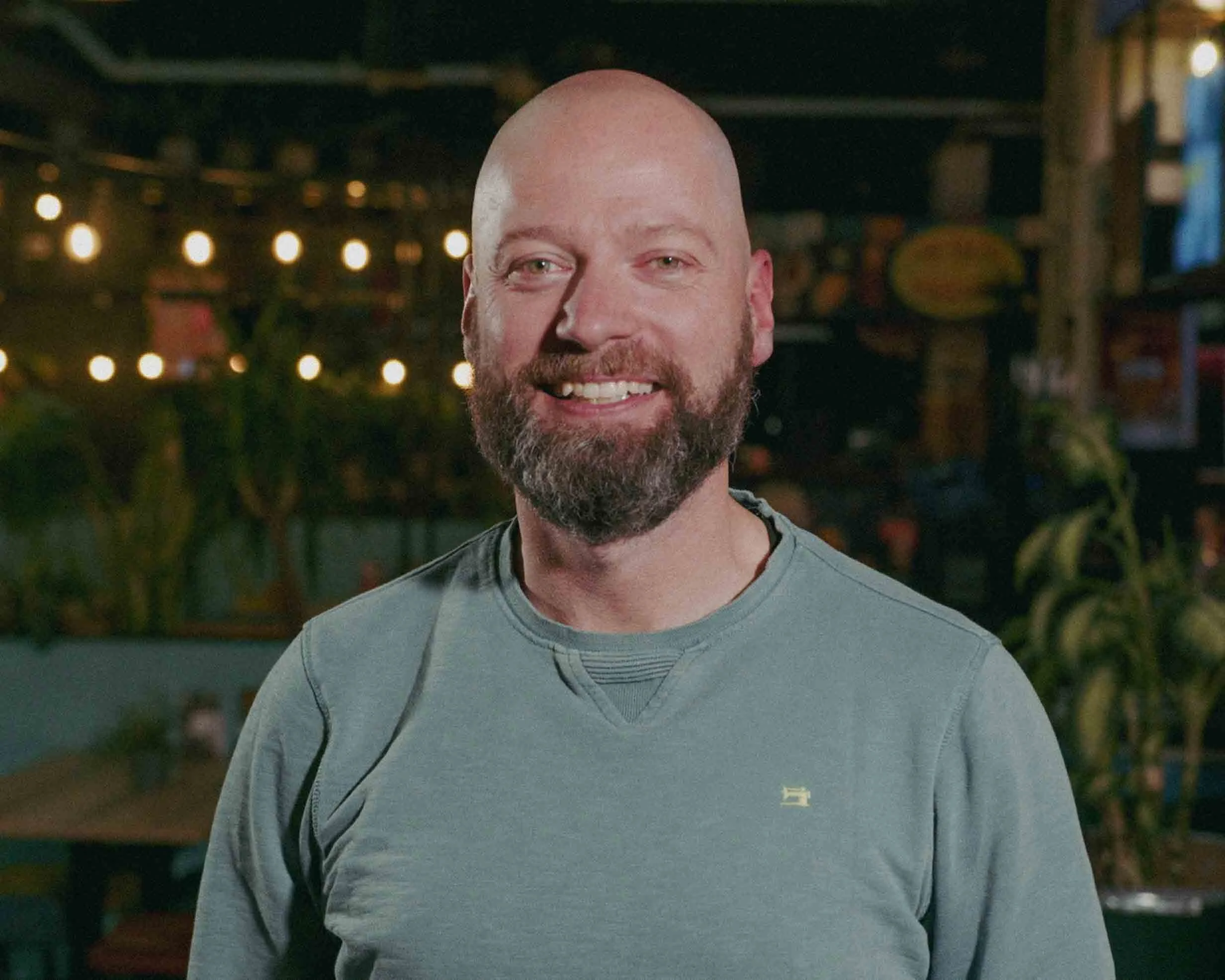 Two middle-aged men relaxing in an outdoor hot tub filled with ice and water, with man's eyes closed and beard visible.