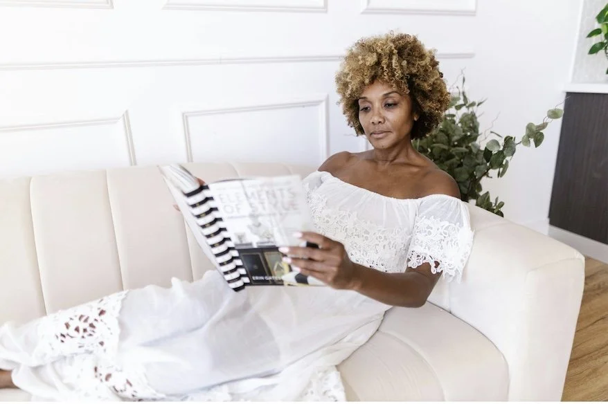 Woman relaxing in a calm, organized home while reading, demonstrating how sustainable organizing systems create more peace, balance, and intentional living.