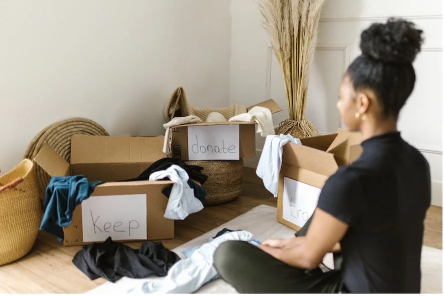 Woman sorting household items into labeled boxes for donation, trash, and keeping during a guided decluttering session using the S.T.I.L.L. Method