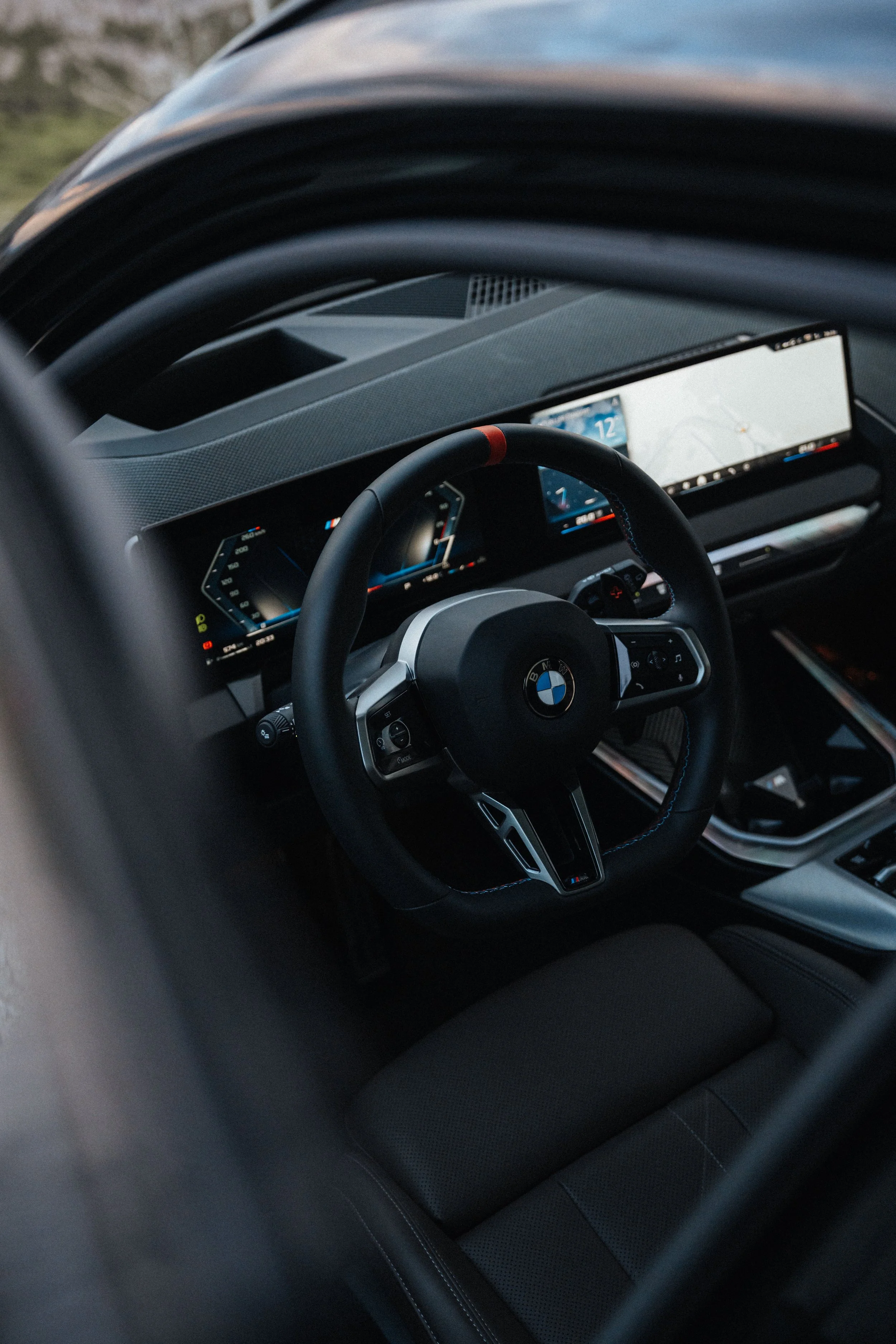 Interior of a BMW car showing the steering wheel and dashboard with digital displays.