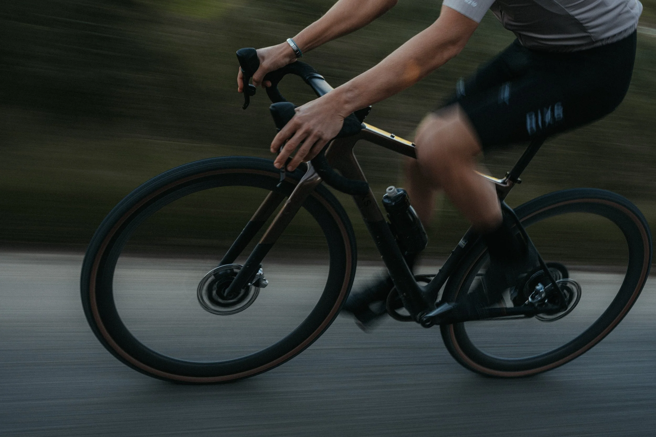 A person riding a black bicycle on a paved road, with blurred background indicating motion.