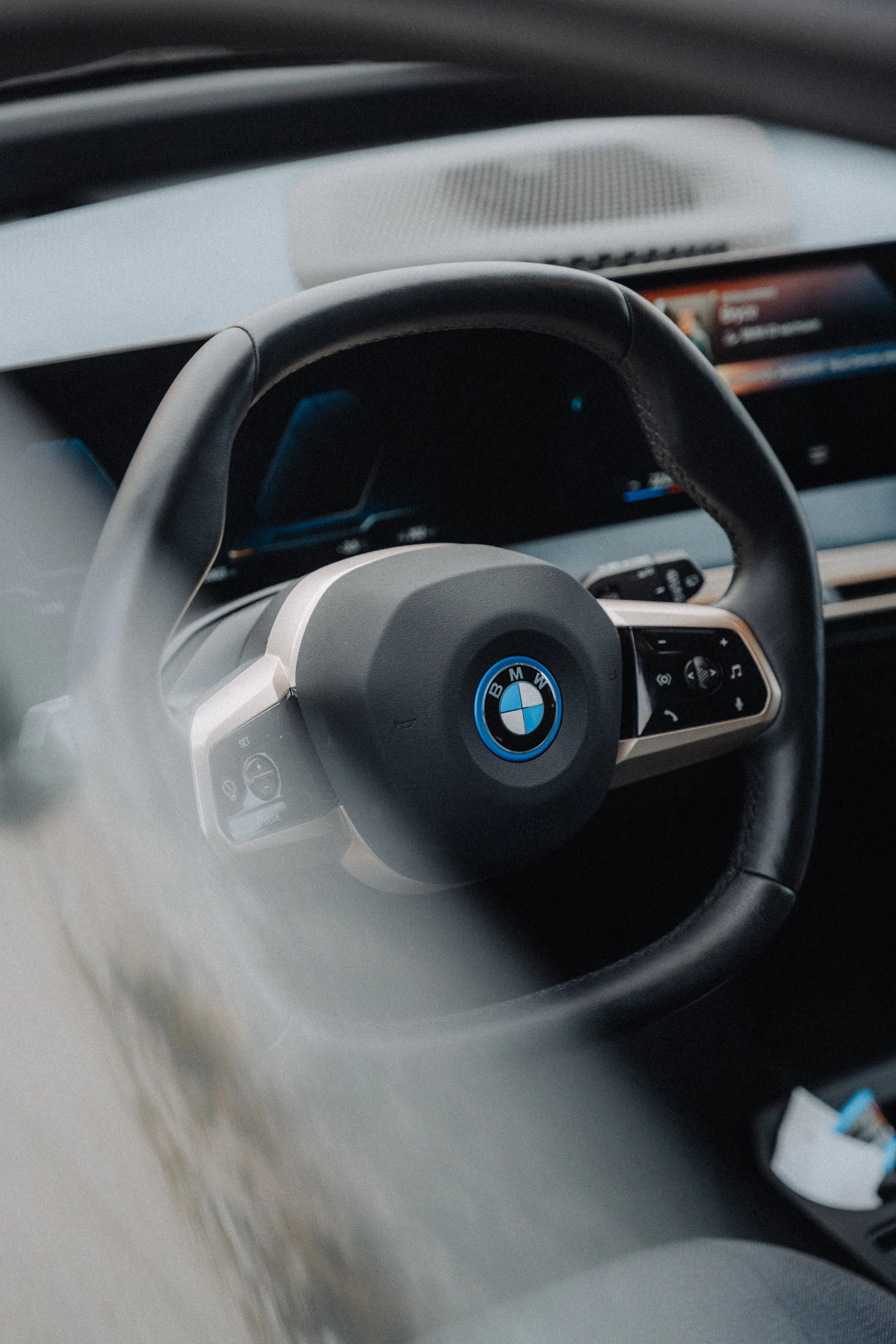 Close-up of a BMW steering wheel with control buttons inside a car.