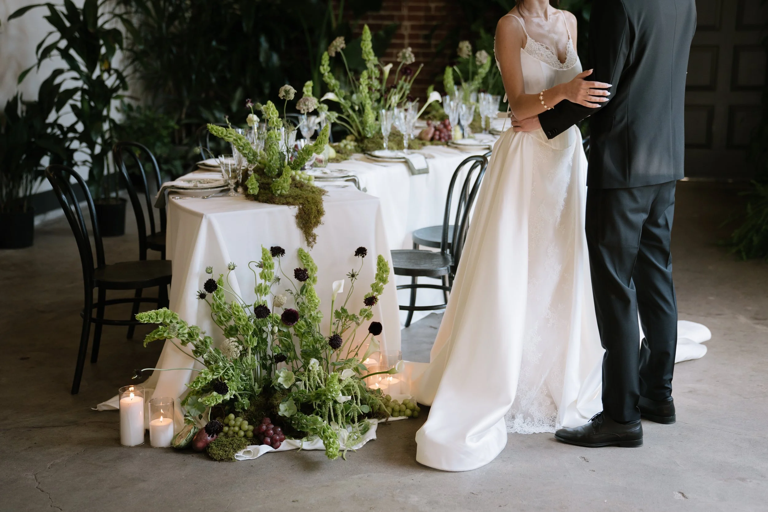 Bride and groom standing together at a wedding reception table decorated with flowers and candles.