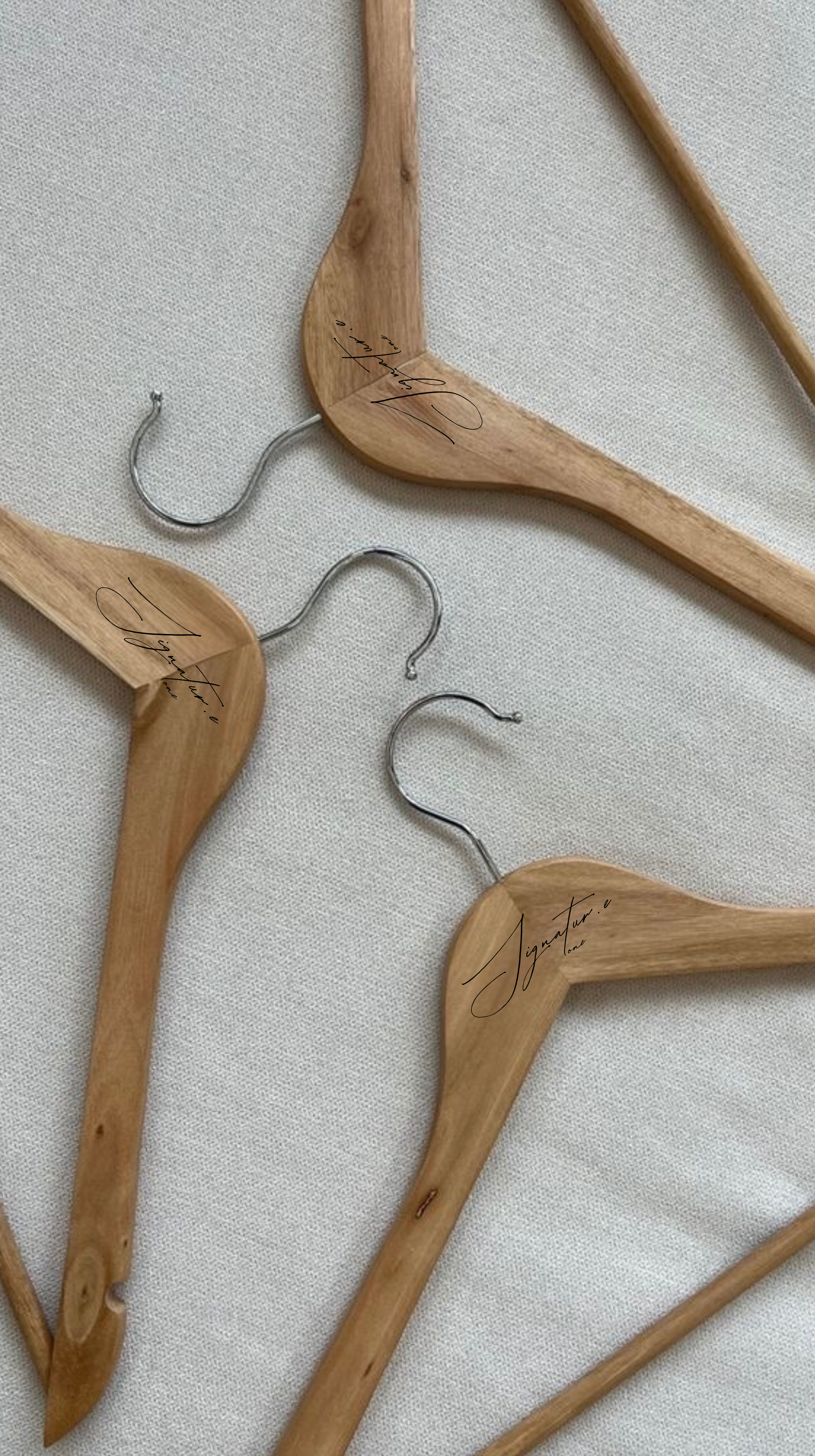 Multiple wooden coat hangers with metal hooks, placed on a light-colored fabric surface.