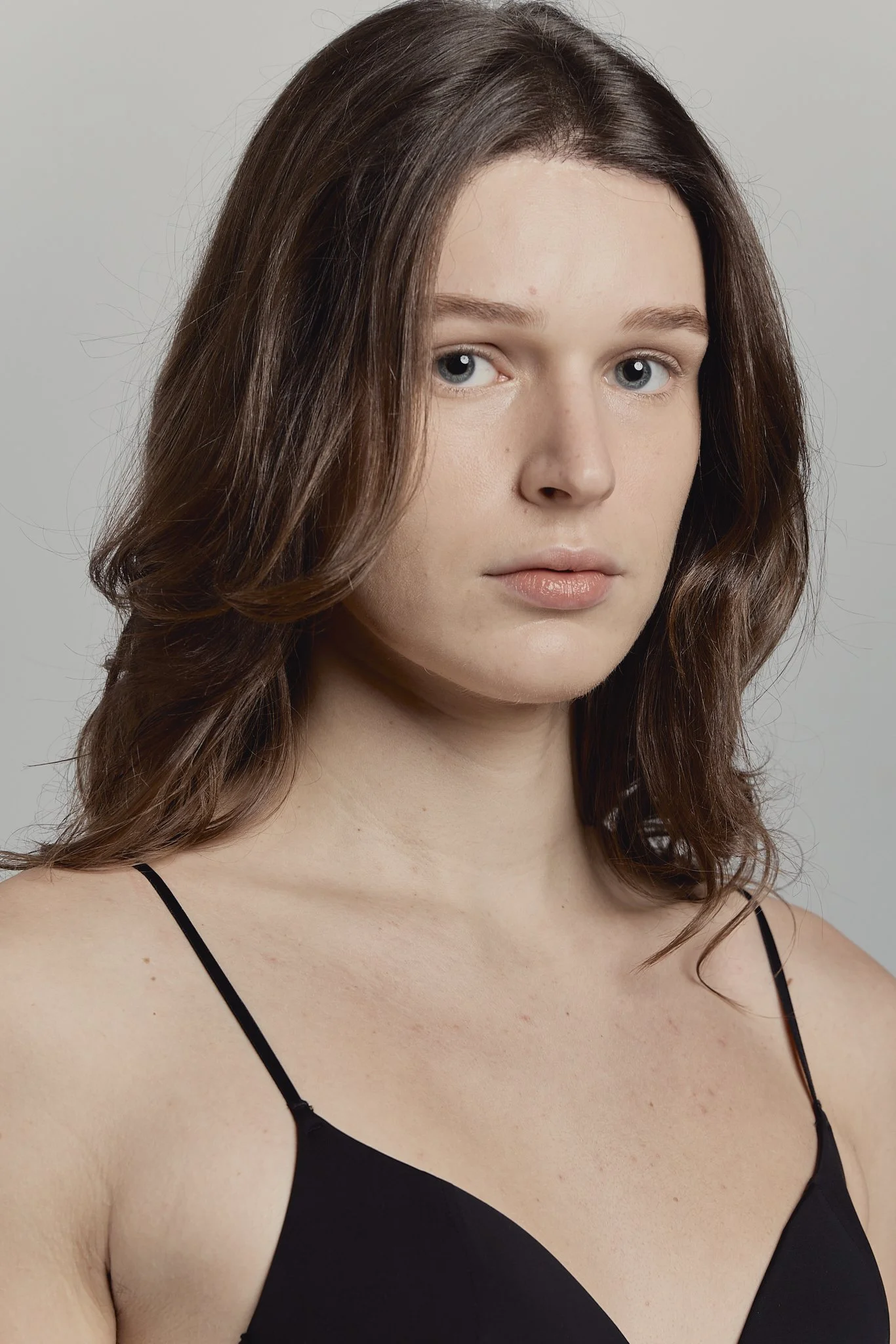 Retrato de una joven con cabello castaño, vestida con una blusa sin mangas negra, mirando hacia la cámara con expresión neutral.
