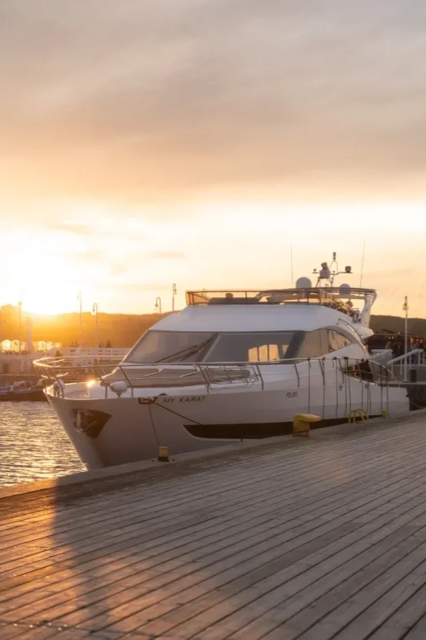 A yacht docked at a marina during sunset with a cloudy sky and calm water.  Private boat charter.  Island hopping.  Phi Phi Islands.  Koh Racha.  Chicken Island.  Best villa in Phuket