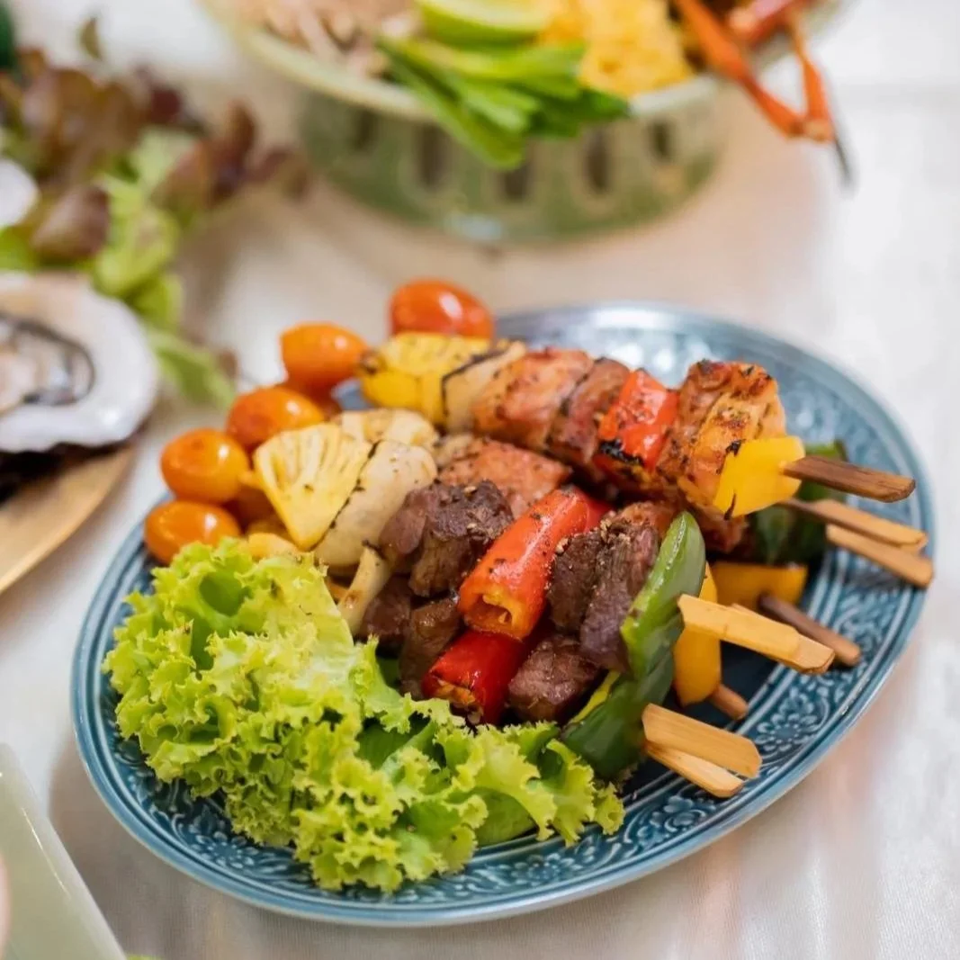 Plate with grilled vegetable and meat skewers, cherry tomatoes, pineapple, cauliflower, and lettuce leaves. Private dining best villa Phuket
