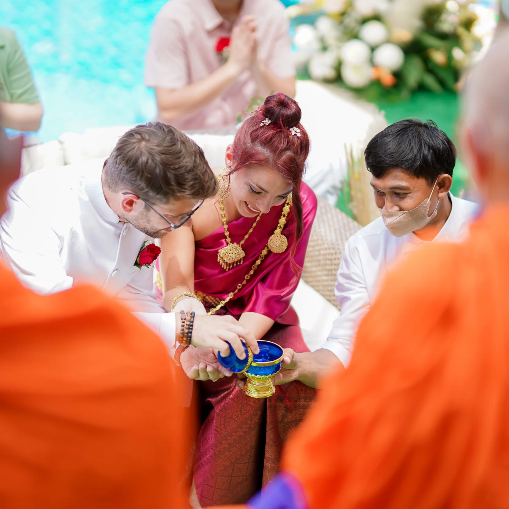 A traditional Indian wedding ceremony with the bride and groom pouring water into a bowl, surrounded by priests and guests in colorful attire.  Best wedding location Phuket villa