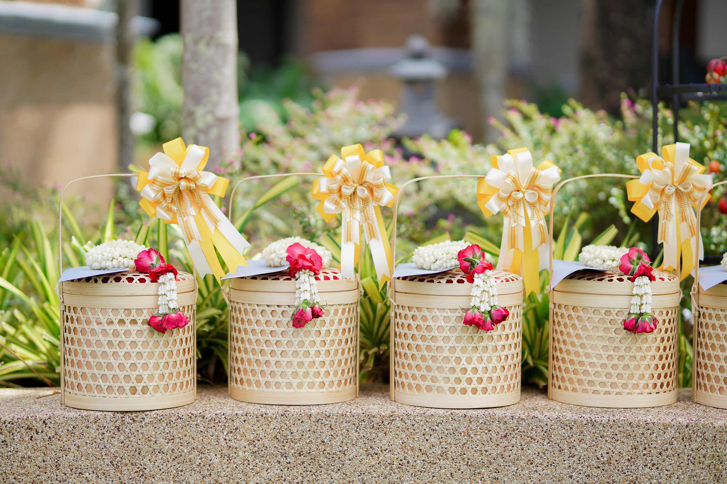 Decorative baskets with flowers and bows on a table outdoors