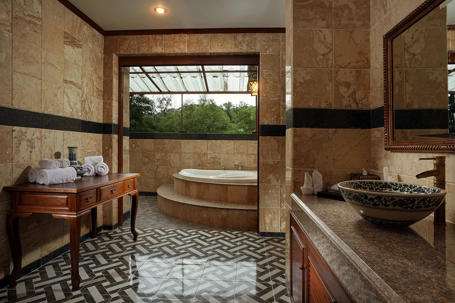 Bathroom with a large bathtub, sink with decorative bowl, mirror, and window showing trees outside.