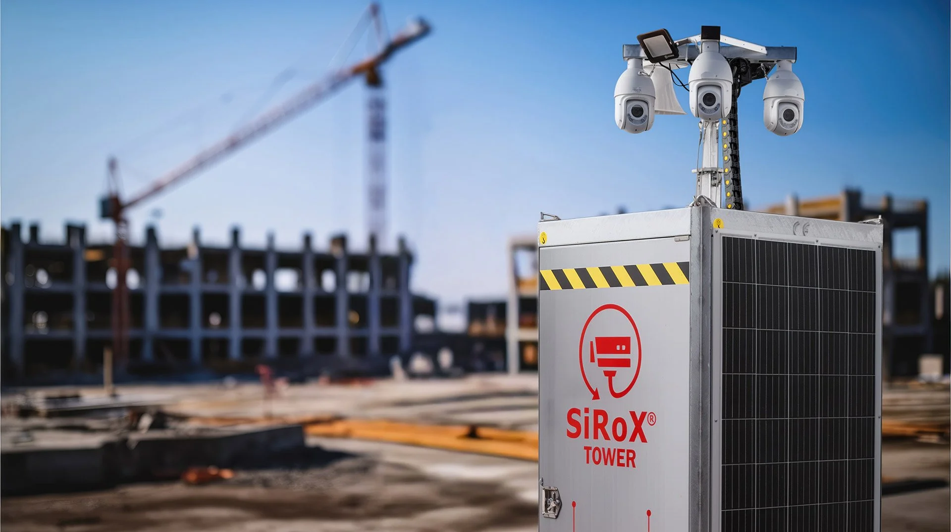 Überwachungsturm auf der Baustelle, im Hintergrund Baugerüst und Kran, sonniger Himmel.